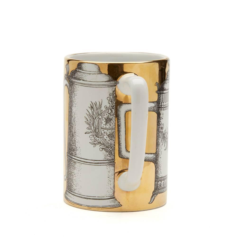 A fine vintage porcelain beer mug by Piero Fornasetti (1913-1988) decorated with three lidded beer steins and a handled beer glass in black outline set within a rich gold surround. The mug has printed marks to the base.