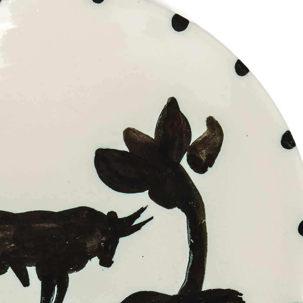 A stunning limited edition Pablo Picasso (1881-1973) Taureau sous l'arbre (Bull Under the Tree) plate in white earthenware clay decorated centrally with a bull standing under a tree in oxidised paraffin (black) and white enamel. The plate has