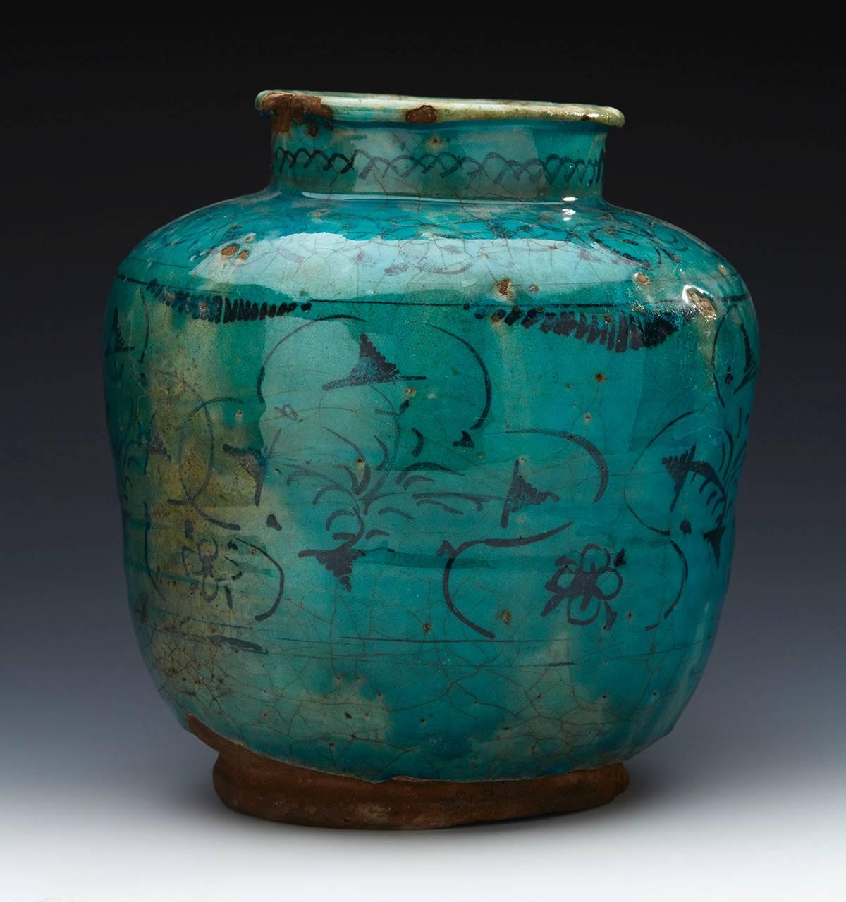 A large antique Middle Eastern vase, believed Kashan, decorated in turquoise glazes with black patterned designs. The earthenware vase is of bulbous rounded shape with a narrow short funnel neck and is not marked with an unglazed foot and base.