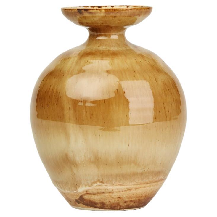 A stunning studio pottery drip glazed vase by Roy Newman made at Pear Tree Pottery in Sheffield. The stoneware vase is of rounded bulbous shape standing on a narrow rounded foot with a narrow top and wide shallow cup shaped top. The vase is