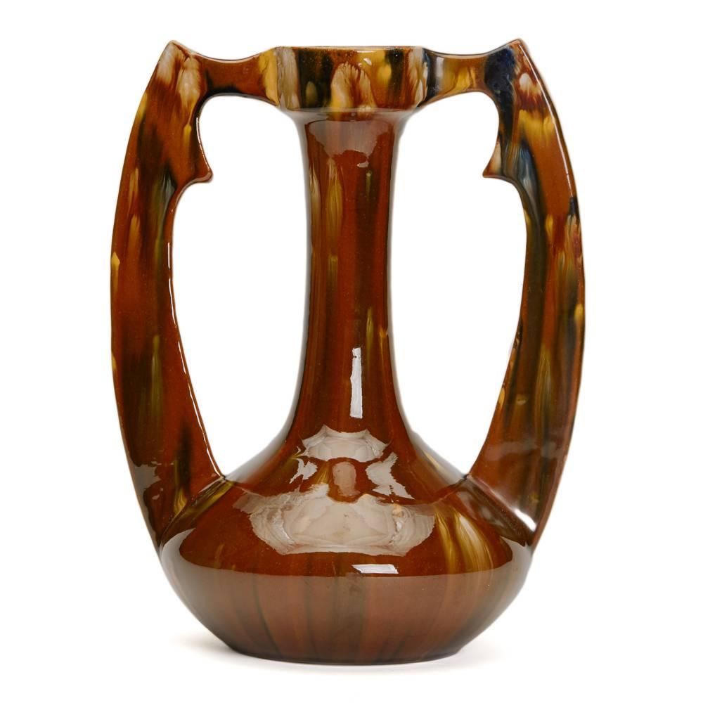 A stunning Art Nouveau French twin handled earthenware vase by Clement Massier decorated with brown, yellowand blue streaked glazes. The vase has an impressed CLEMENT MASSIER GOLFE JUAN.