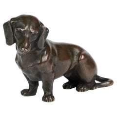 Encantadora figura de perro salchicha sentado de bronce antiguo