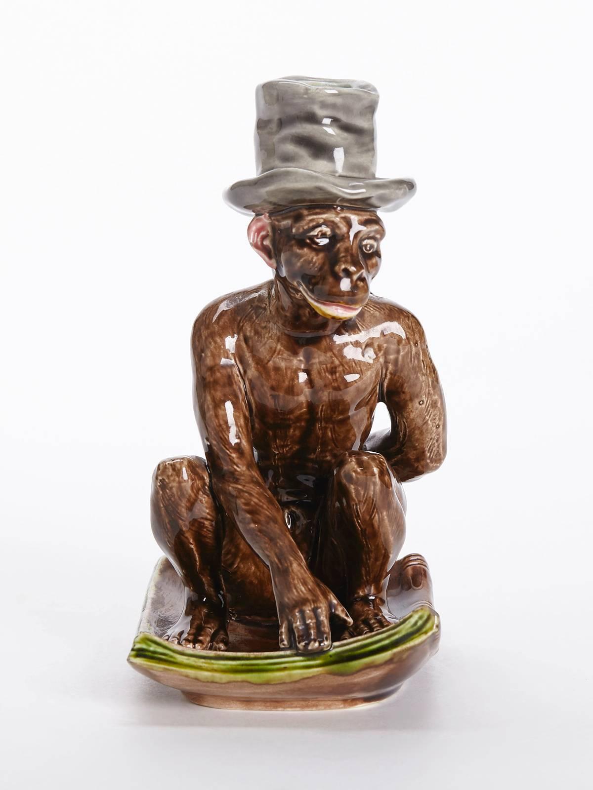 An extremely rare antique French Sarreguemines Majolica monkey candlestick or chamberstick sat on a manuscript titled Darwin. The figure is exceptionally well modeled with excellent detail and portrays the monkey seated on the manuscript and wearing