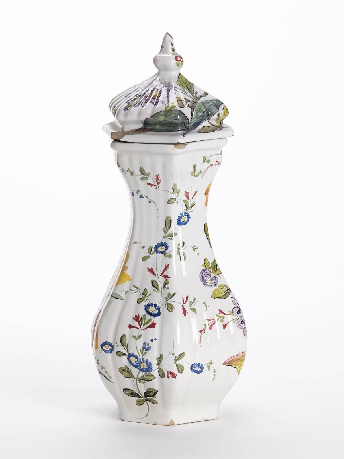 A fine and elegant antique Italian Le Nove floral painted faience vase and cover. The earthenware hexagonal shaped vase has a moulded ribbed body exquisitely hand-painted with bright floral designs on a white ground. The vase has a similarly shaped