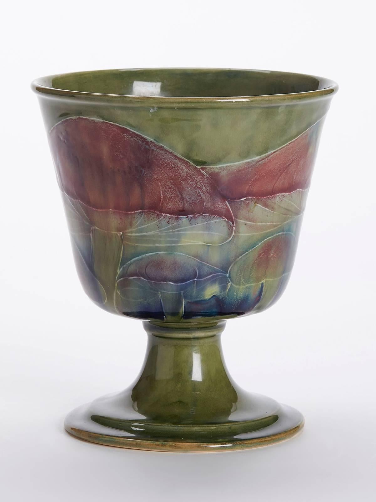An extremely rare William Moorcroft Claremont pattern goblet vase of conical shape mounted on a rounded pedestal foot. The vase is decorated with tubelined mushrooms in streaked brown and blue glazes on a green ground. Probably retailed by Liberty &
