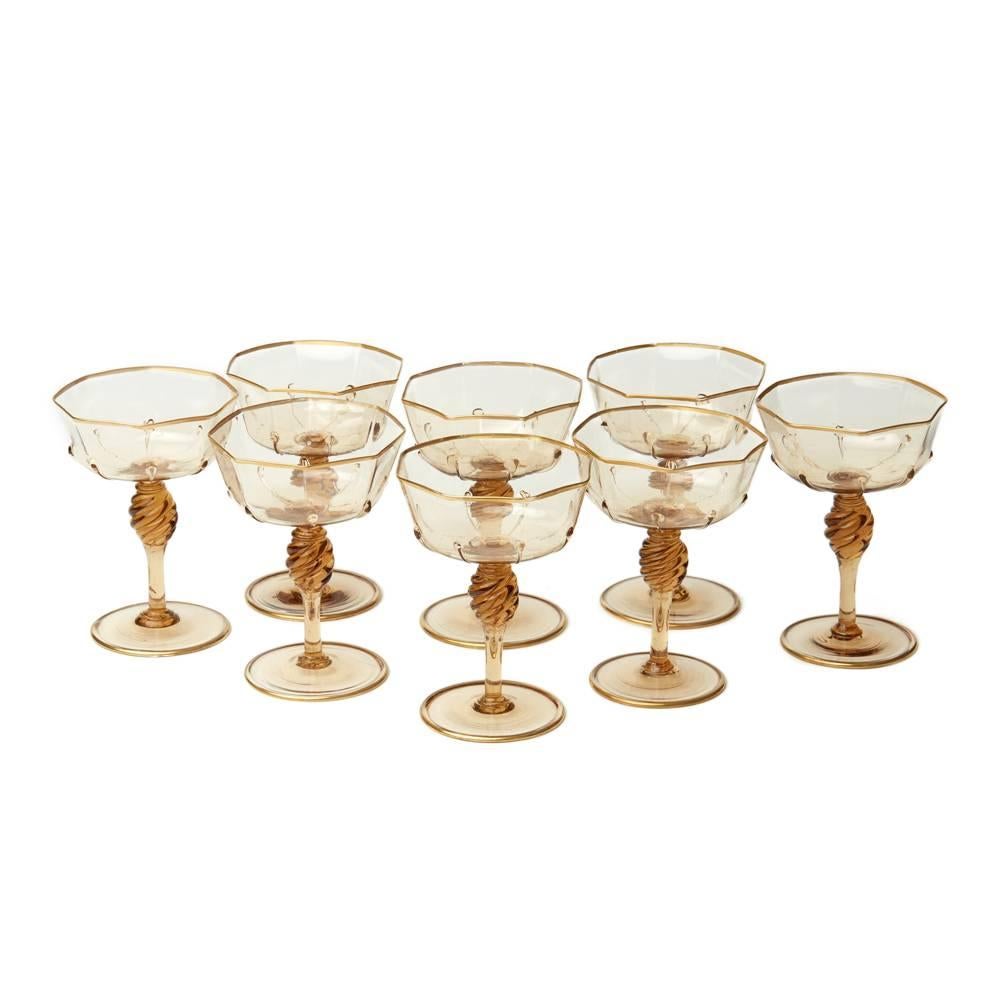 A very fine set of eight Murano MVM Cappellin amber champagne/prosecco glasses with wide and shallow octagonal bowl with applied tear drops to a wrythen knopped stem and spreading circular foot and with gilded edging. The glasses are not