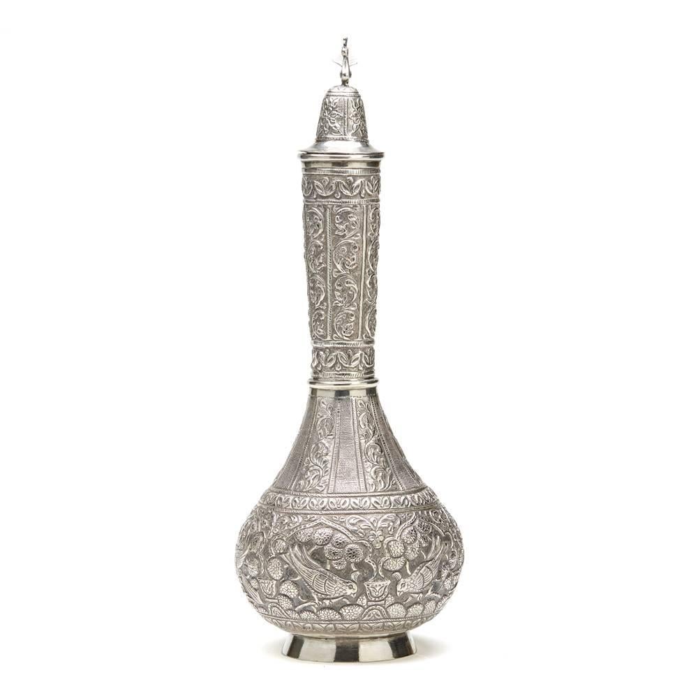 A fine antique Indo-Middle Eastern silver rose water bottle and cover embossed with birds perched amidst flowering stems with scrolling leaf panels to the neck. The bottle has a domed cover embossed with flowers and attached by a silver chain with a