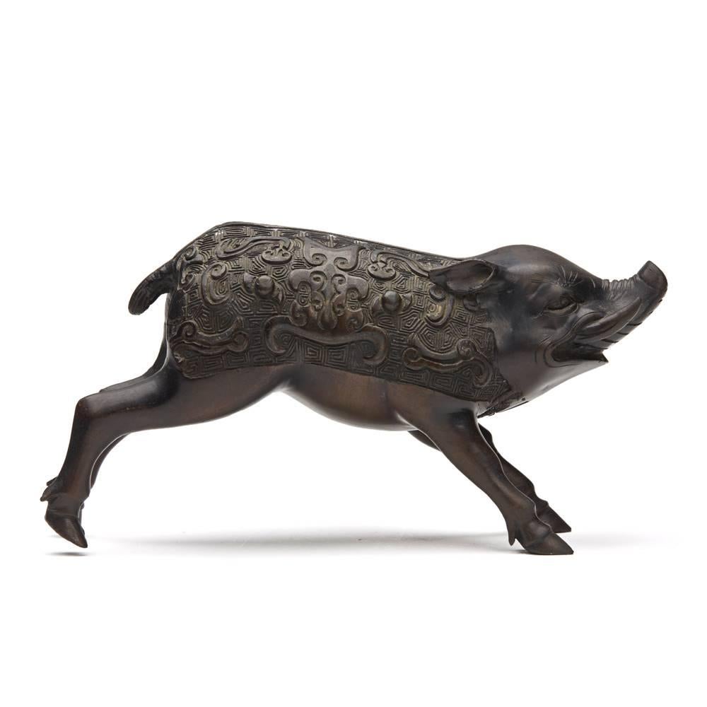 A fine and unusual antique Japanese Meiji bronze figure of a wild boar, the body with a detailed patterned relief moulded design. The running male boar has good facial features with extended canine teeth and is not marked.
