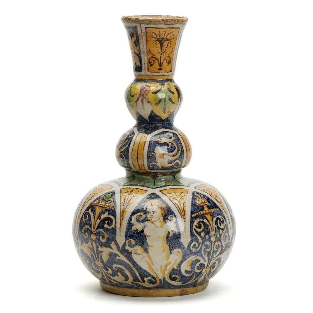 Un étonnant et rare vase italien antique à triple gourde en poterie Maiolica peint à la main avec des motifs figuratifs stylisés classiques et des rinceaux dans des couleurs typiques de Maiolica : jaune, bleu, vert, brun et blanc. Le vase en faïence