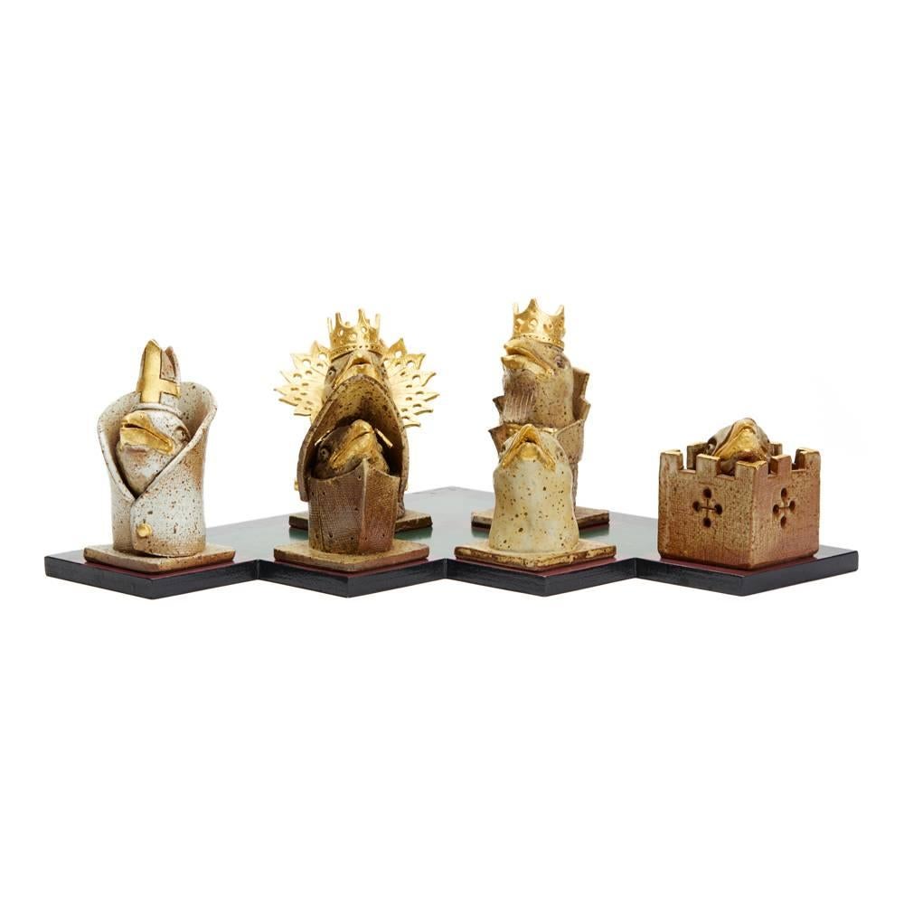 An unusual and stylish Kenneth Breeze Studio Pottery chess pieces and board sculptural installation comprising of six chess pieces and a hand-painted cut-out board. The chess pieces include a king, a queen, a bishop, a knight. A rook and a pawn each