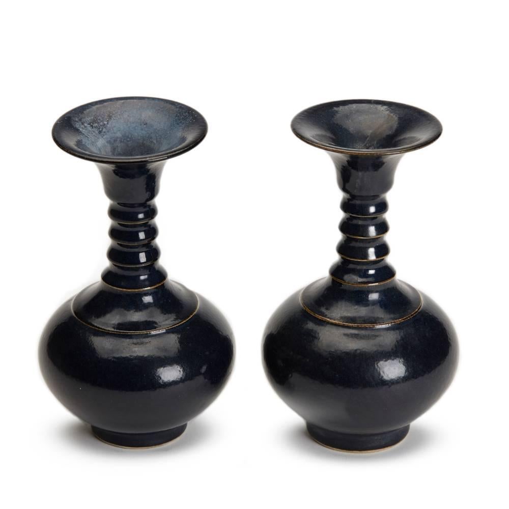 A pair of Chinese blue glazed vases with collared necks and finely incised marks to the base dating from the 20th century. This pair of porcelain vases Stand on a narrow unglazed foot rim with a recessed base and have a rounded bulbous body with a