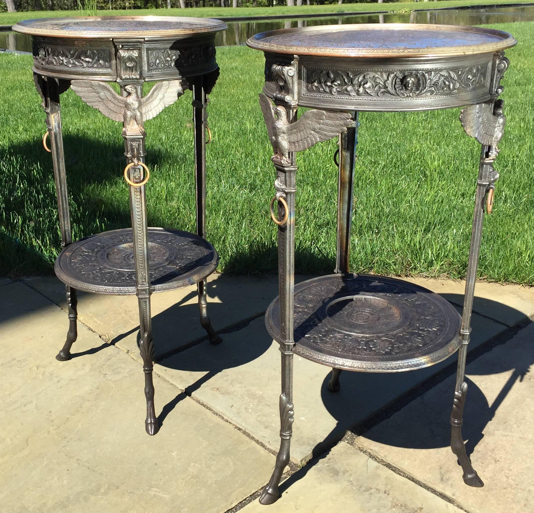 This most unusual pair of neoclassical polished and patinated cast iron side tables date to the late 19th century. 
The top is silver gilt with elaborate two-dimensional reliefs of winged Griffin between foliate motifs outlined by Meander and