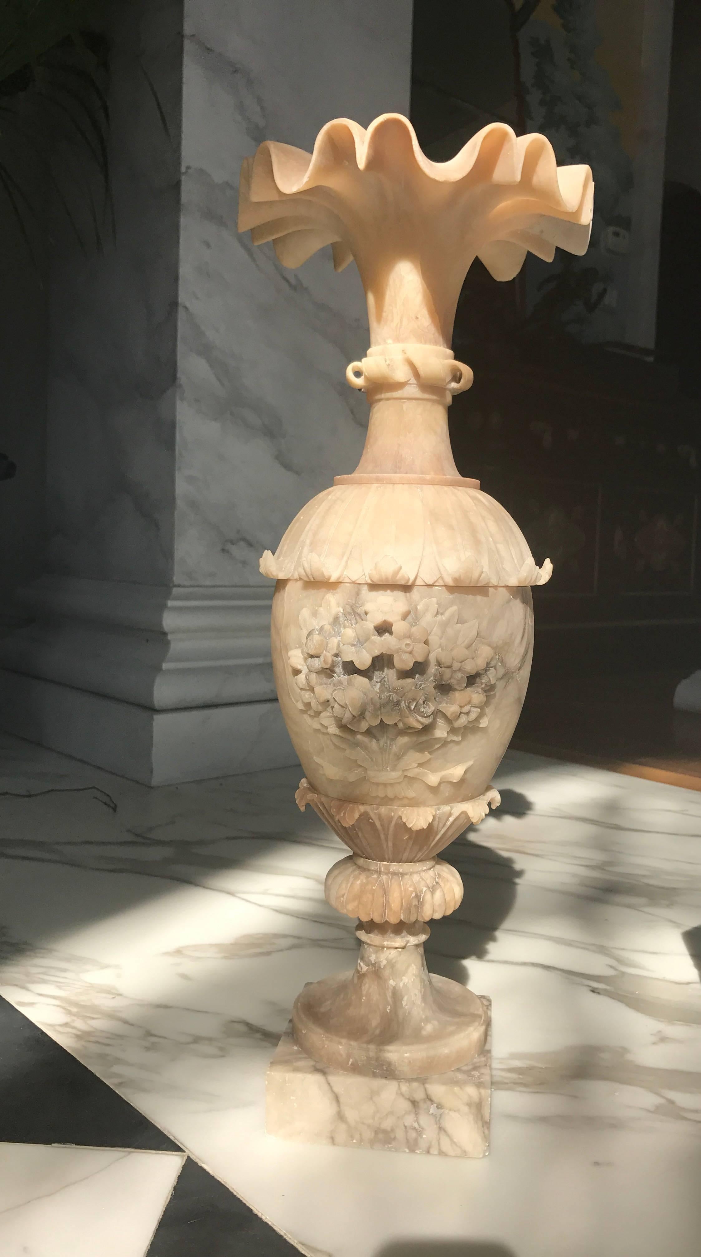 This large alabaster vase was manufactured in Italy during the grand tour period, circa 1870. The top rim has an extravagant scallopped edge
The backside is plain and the front has floral carvings, so it can be used either way, depending on the