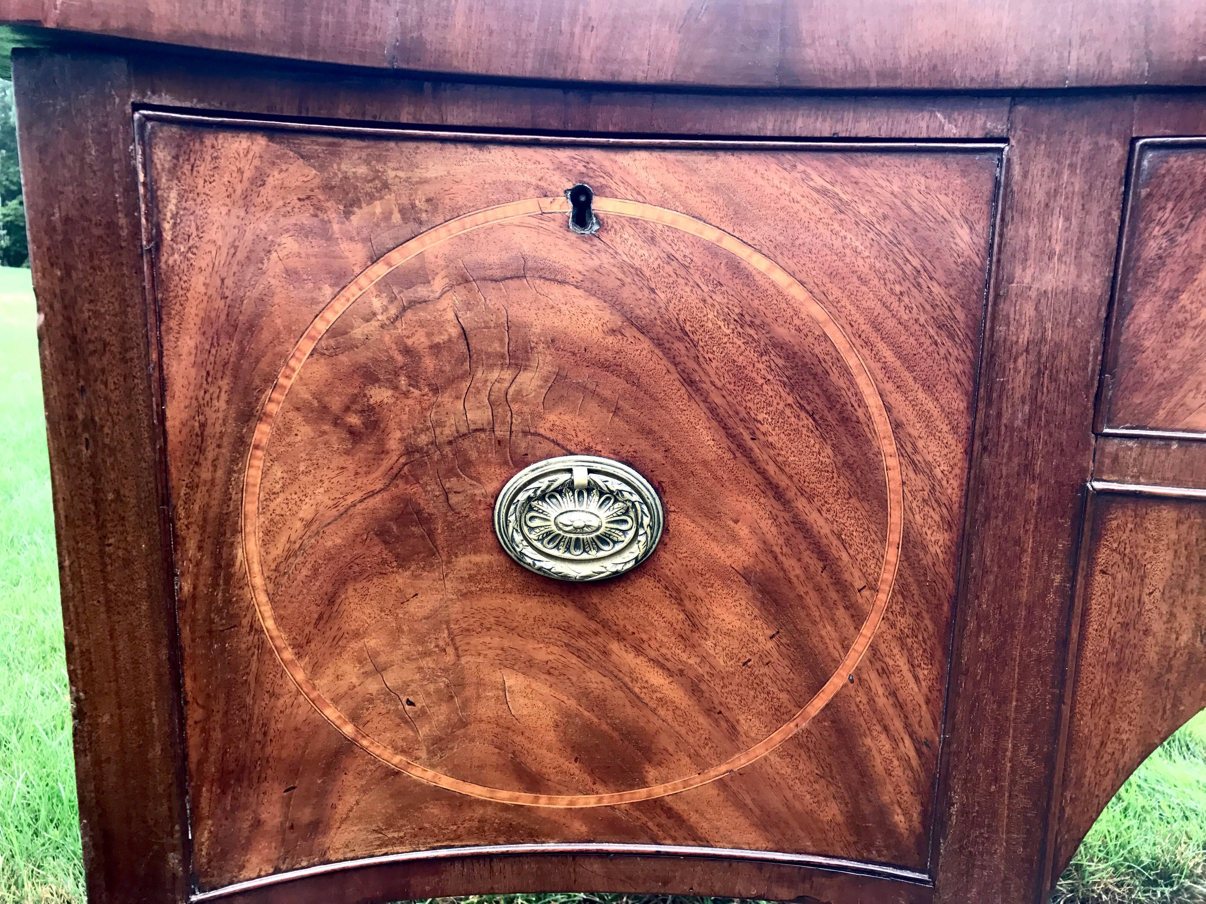 This elegant mahogany early 19th century English George III sideboard has a beautiful serpentine front with at central arch.
The color is a caramel brown mahogany.