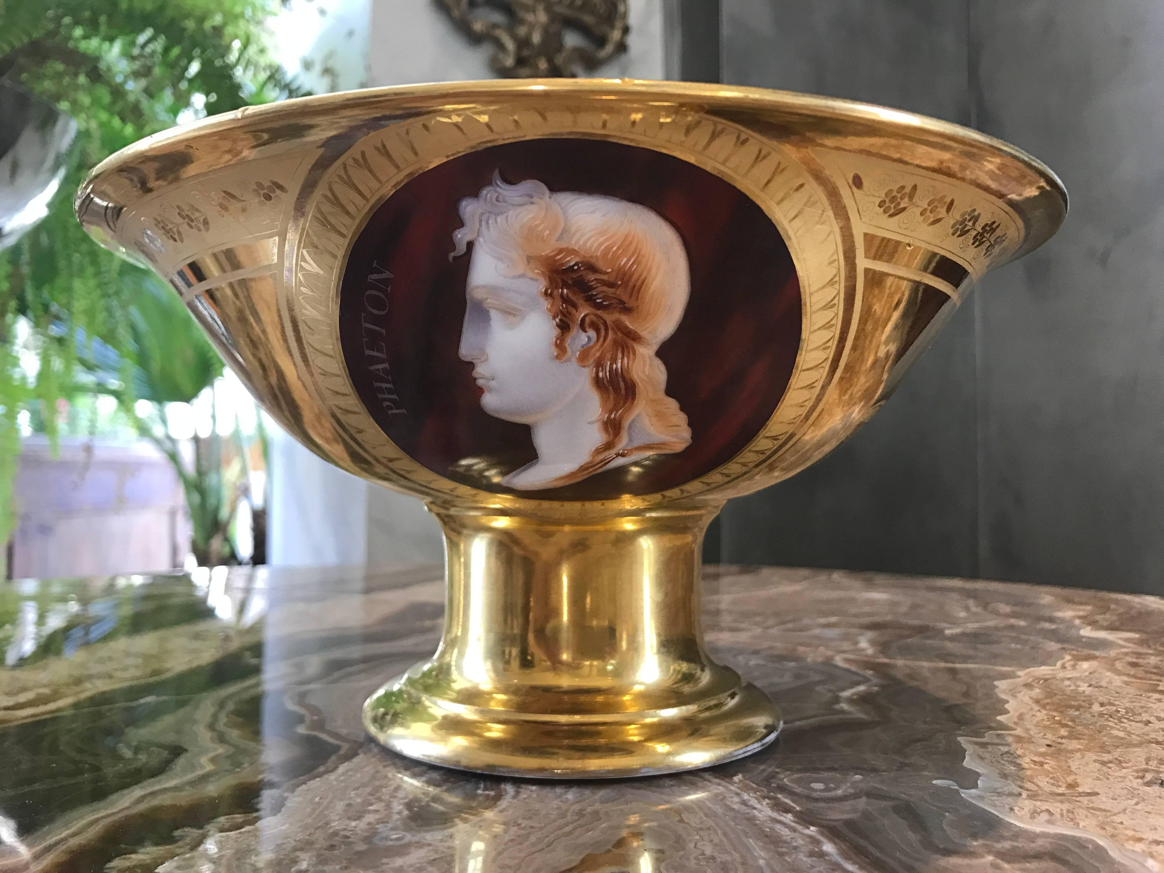stunning porcelain fruit bowl fit for an Emperor. One side displays in the style of a cameo on a rich burgundy background the handsome Profile of Phaeton, son of Apollo/Helios, the other side the profile of Eagle.
The underside shows orange markings