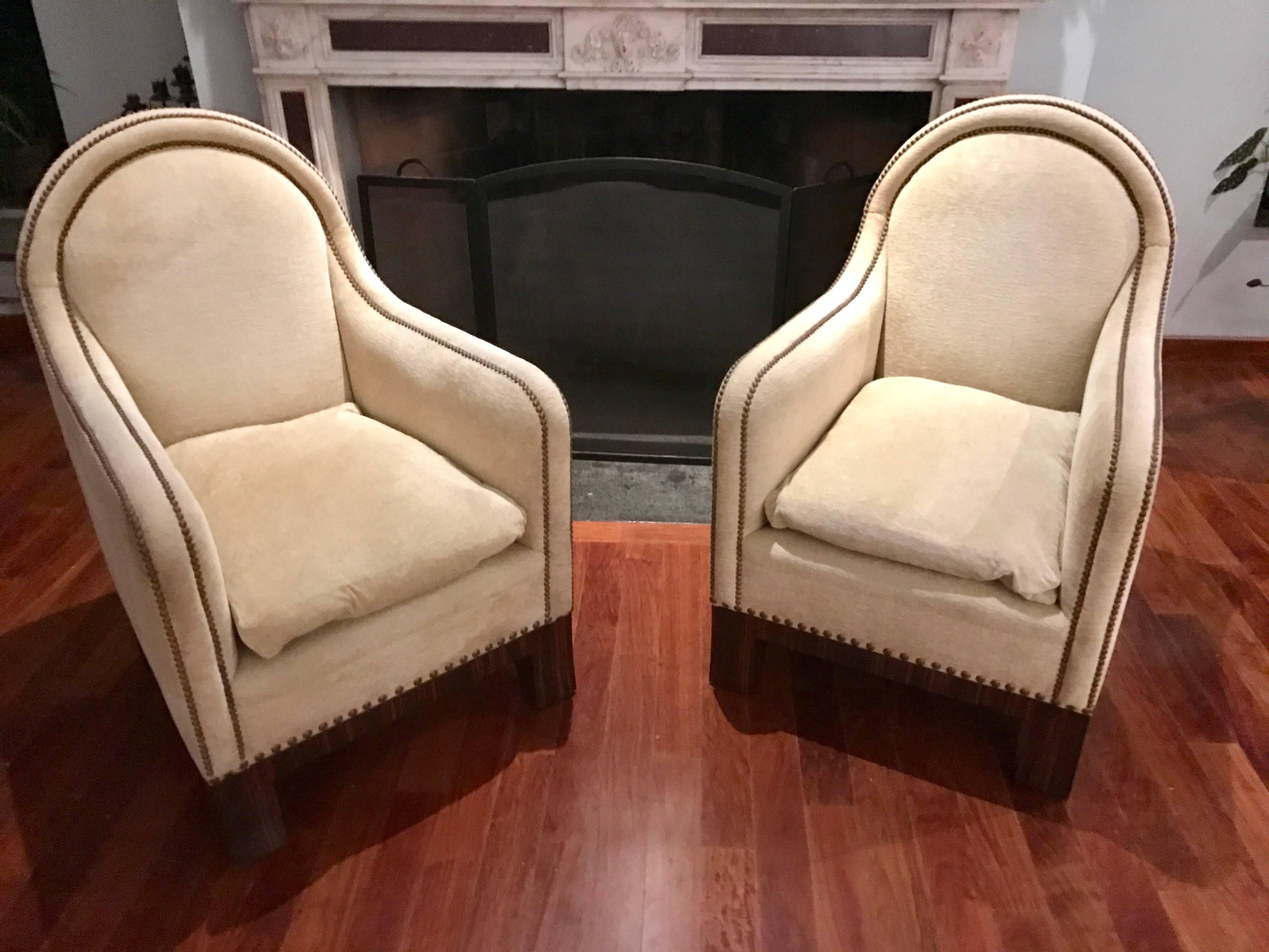 This elegant Pair of Mid-Century Modern Lounge Chairs with their high backs and deep seats are the place to mingle.
Once you sit down it will be hard to get up again.
The Rosewood veneered feet and brass tacks give them there stylish looks. 
     