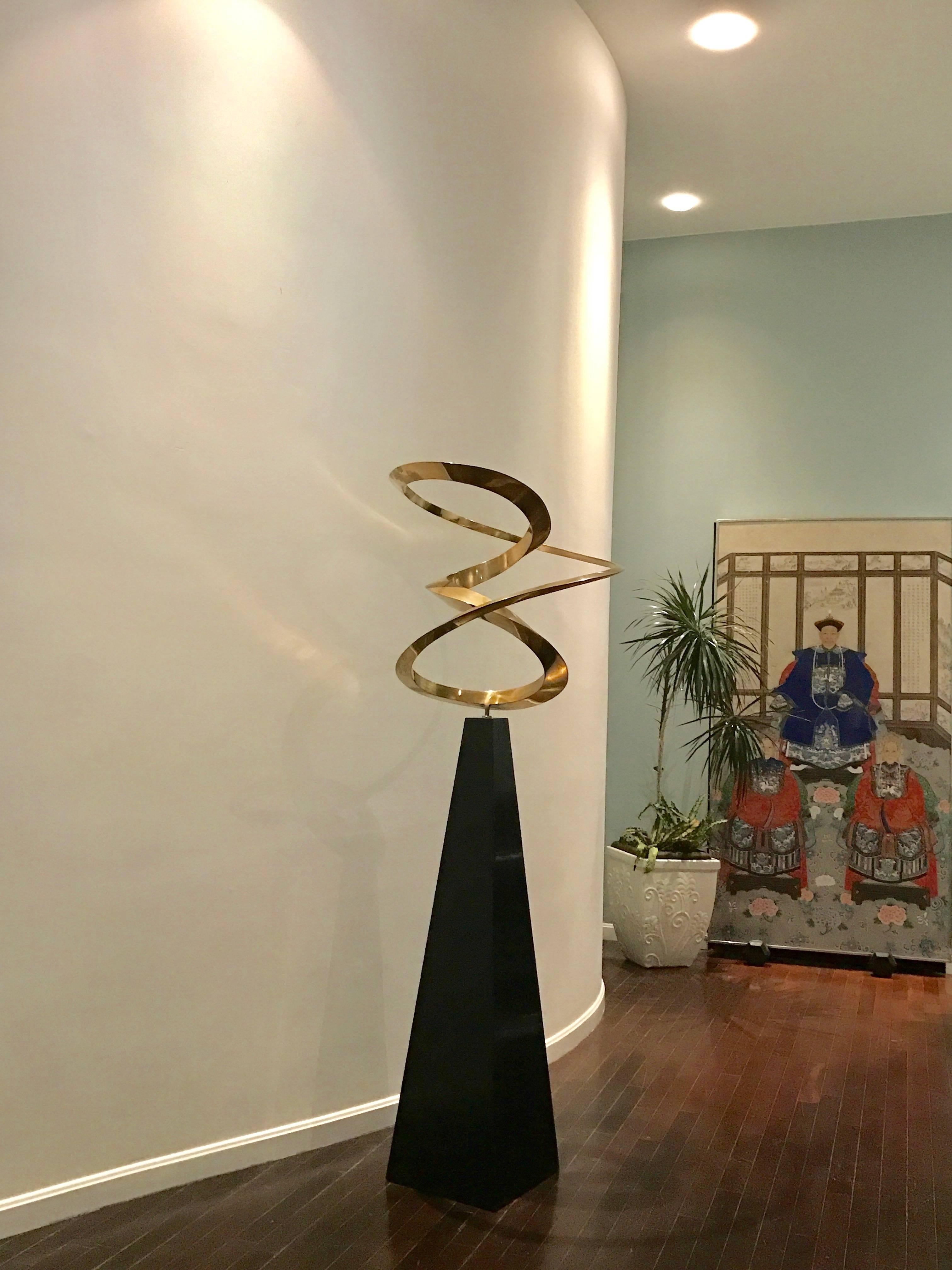 This Beautiful gold-tone Metal Spiral Sculpture rotating on a black lacquered wooden base is by Robert Perless (American B. 1938),  who is known for Kinetic Art. His work is represented in Major Institutions, Airports and Museums including the