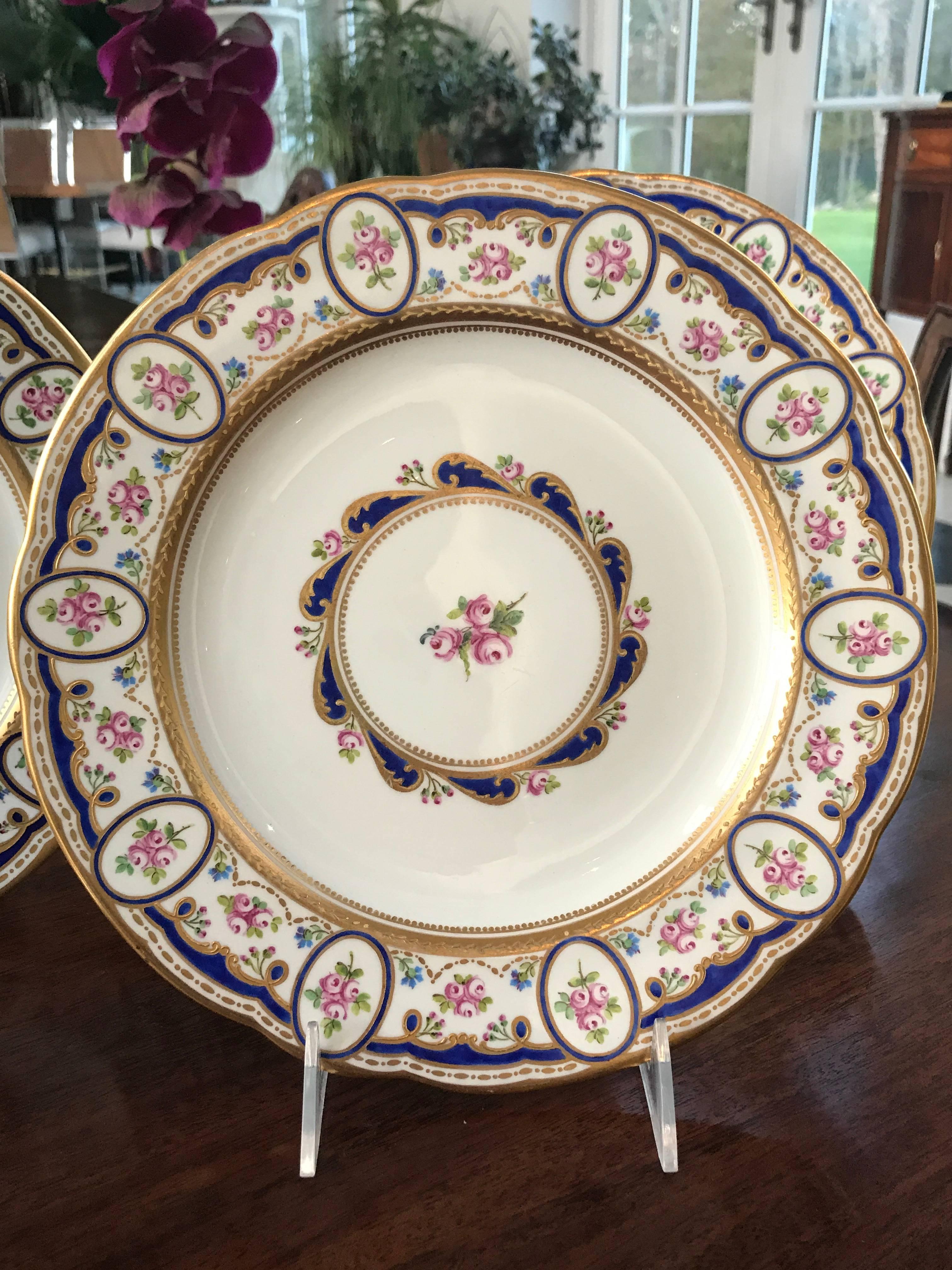 This gorgeous Set of 12 Porcelain Dinner Plates was custom created by Wedgwood in 1900 to match a pattern identical to ones of Sèvres. 
(We have a set of six of such plates by Sèvres)
These hand painted plates have pink roses and blue corn flowers