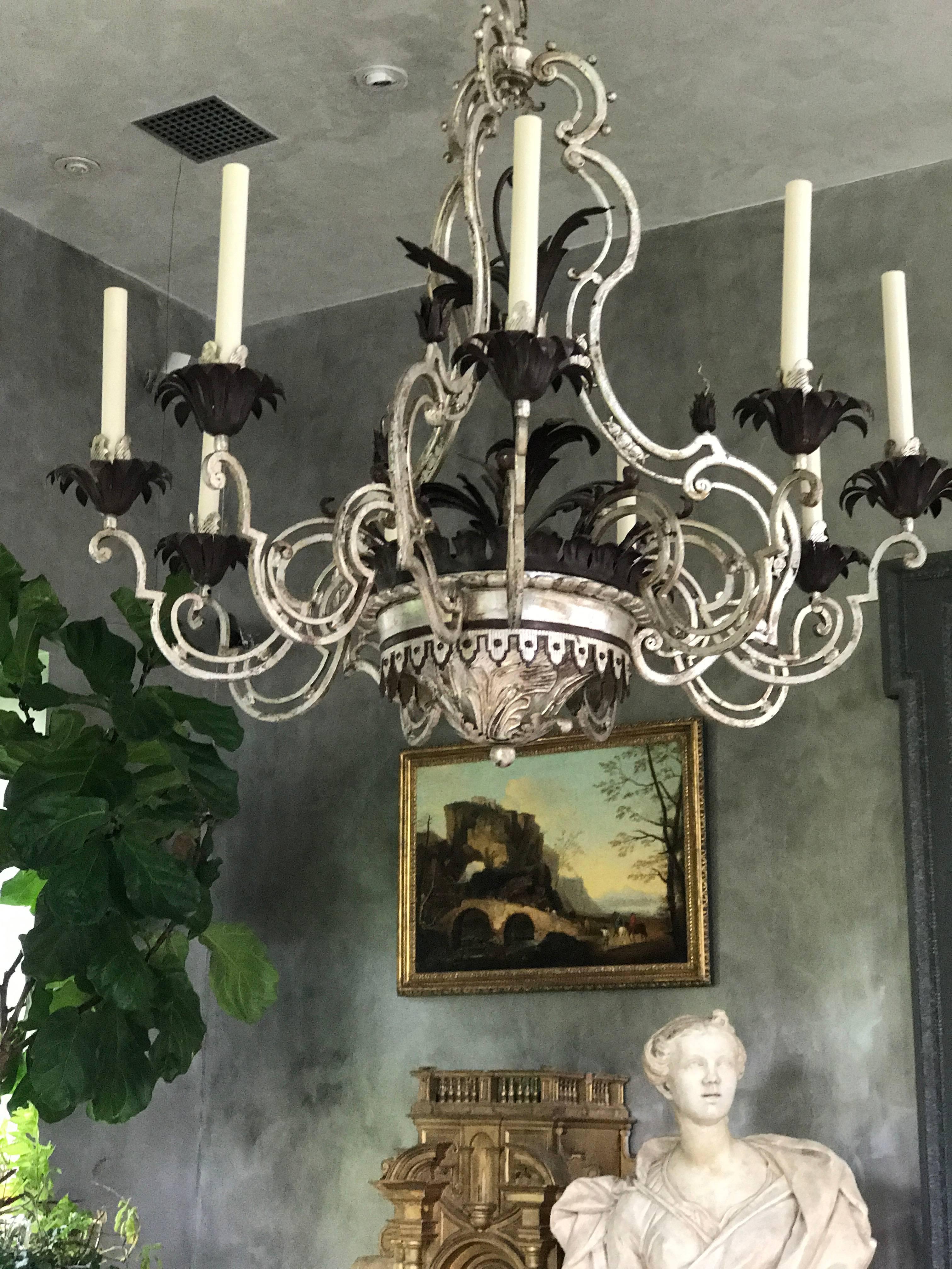 This beautiful wrought iron & tôle nine-arm chandelier was created in the 1940s and inspired by a Louis XV French Chandelier form. The aged silver patina gives this Chandelier it's extraordinary look.
