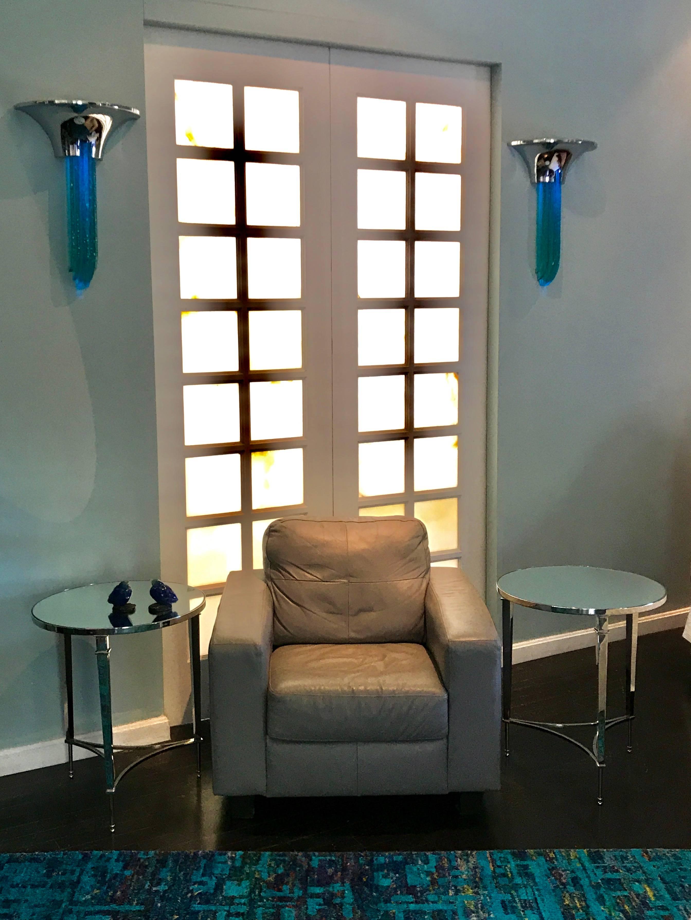 A stunning and rare Pair of "Purcell" Chrome Wall Sconces designed by Karl Springer. This form comes in a few color and material variations.
The Crome and Teal Glass being one of the rarest ones to find. Lit up they look like icycles.
The