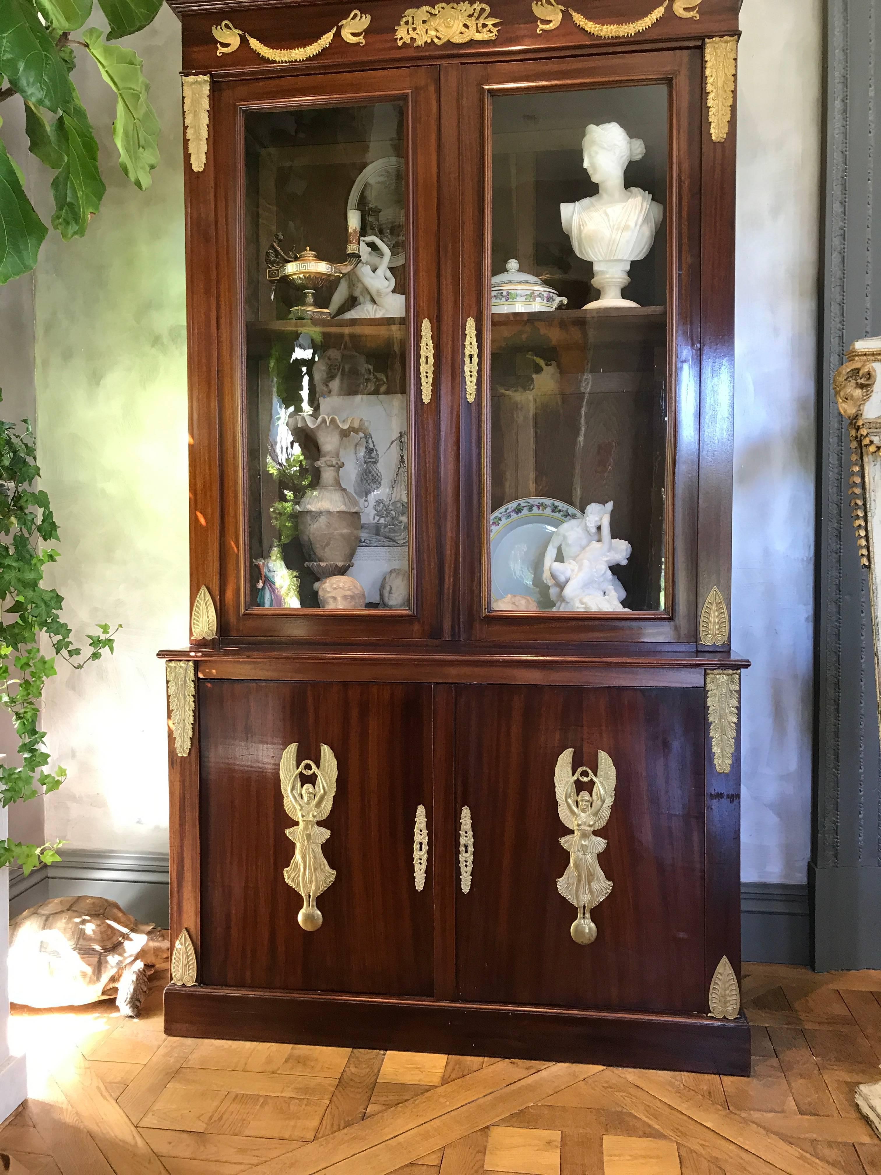 This beautiful pair of mahogany Empire bookcases is decorated with gilt bronze mounts portraying armorial motifs, winged Nike figures, swans and garlands.
The glass doors are original.