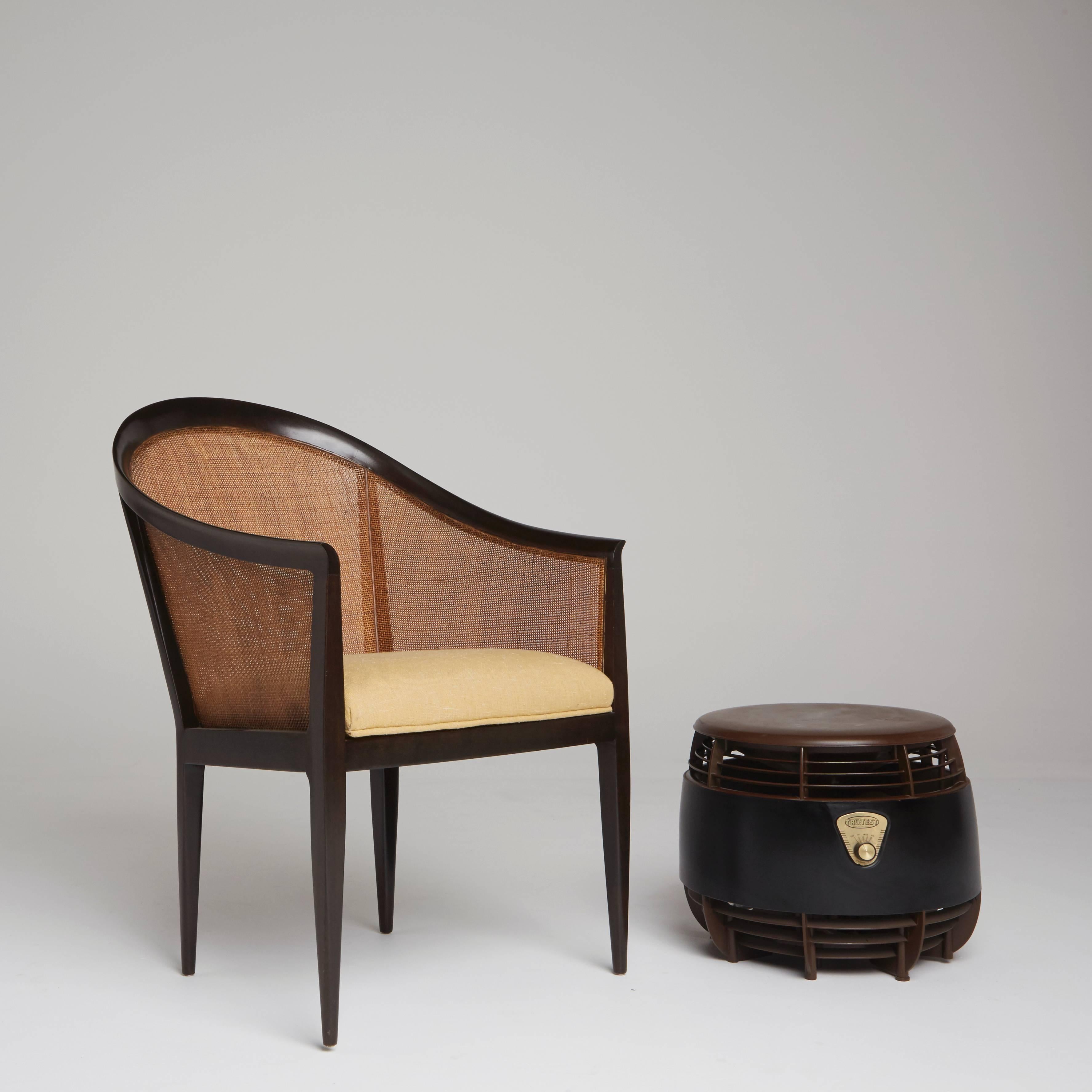 Kipp Stewart designed this elegant and sophisticated armchair in the 1960s for influential American manufacturer, Directional Furniture. The curvature of the ebonized walnut frame borders each chair's impeccable caning, and the cream and soft yellow