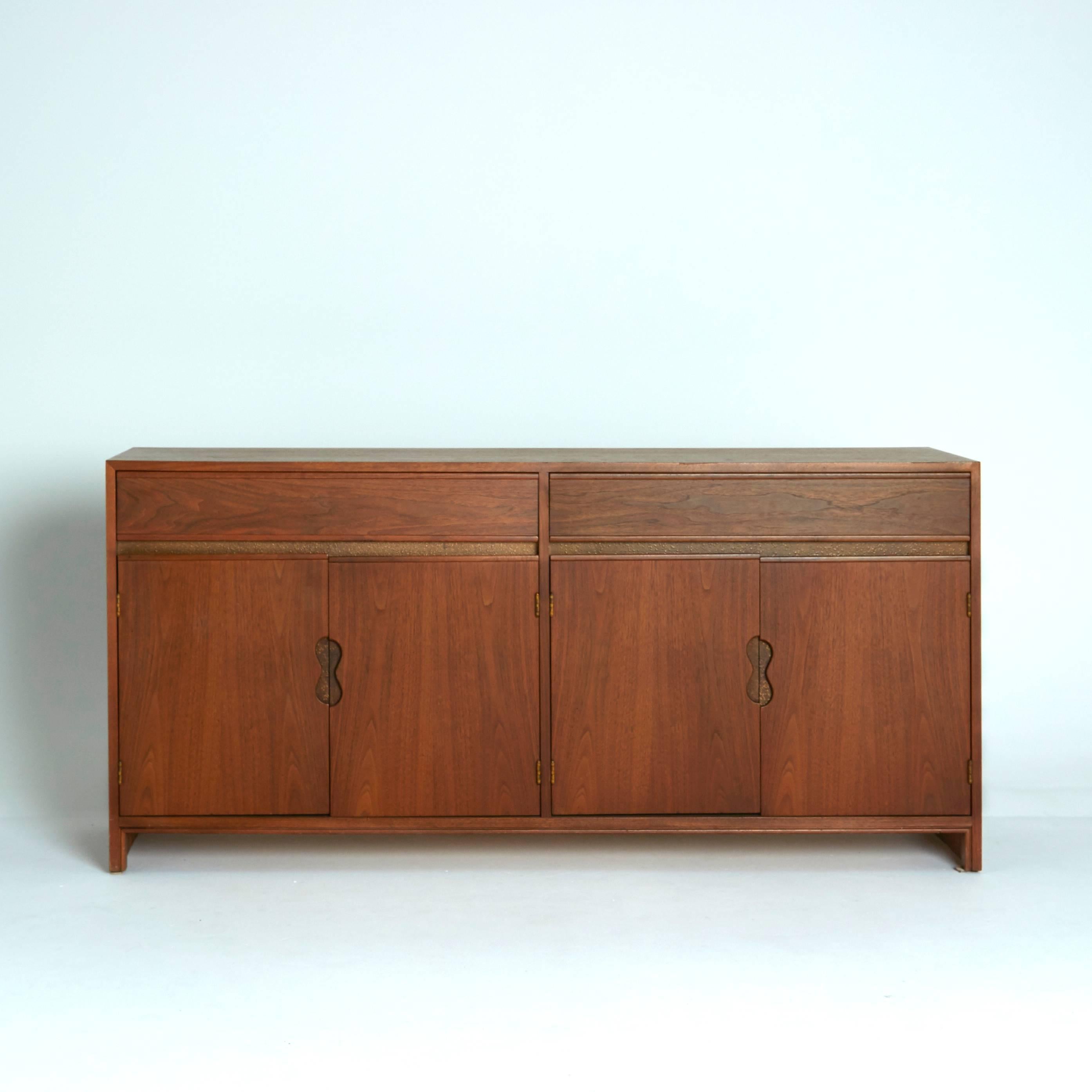 Designed in the 1950s by renowned Hungarian designer Paul Laszlo and manufactured by Brown Saltman, this credenza is a very rare and special piece. The rich grain of the walnut and the biomorphic shape of the door handles make this piece stand out