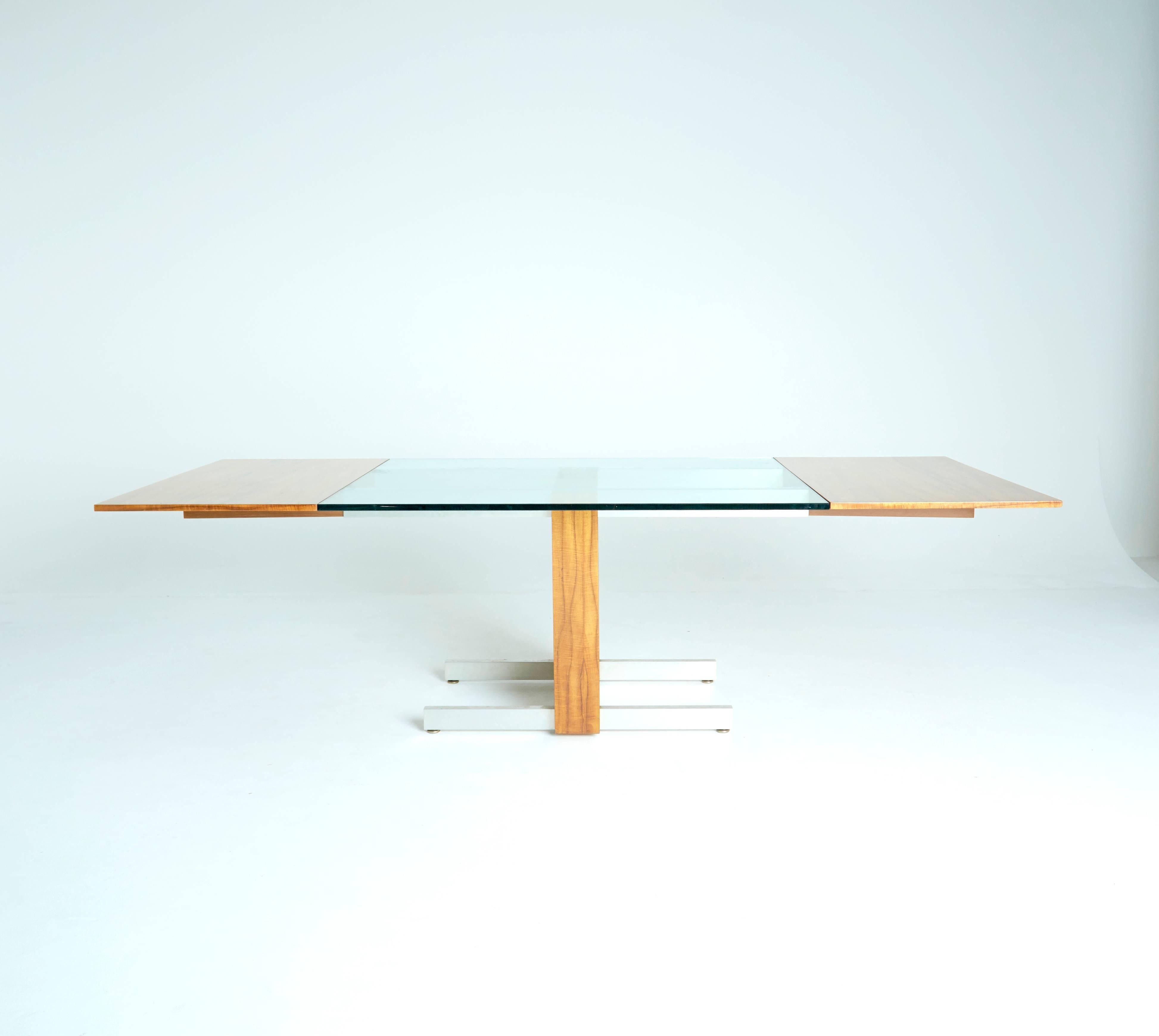Designed by Vladimir Kagan in the 1960s, this cubic table's sleek, modern design keeps it relevant and prominent throughout the decades. This table is perfect either as a dining table or a conference table, as two removable wood leaves border either