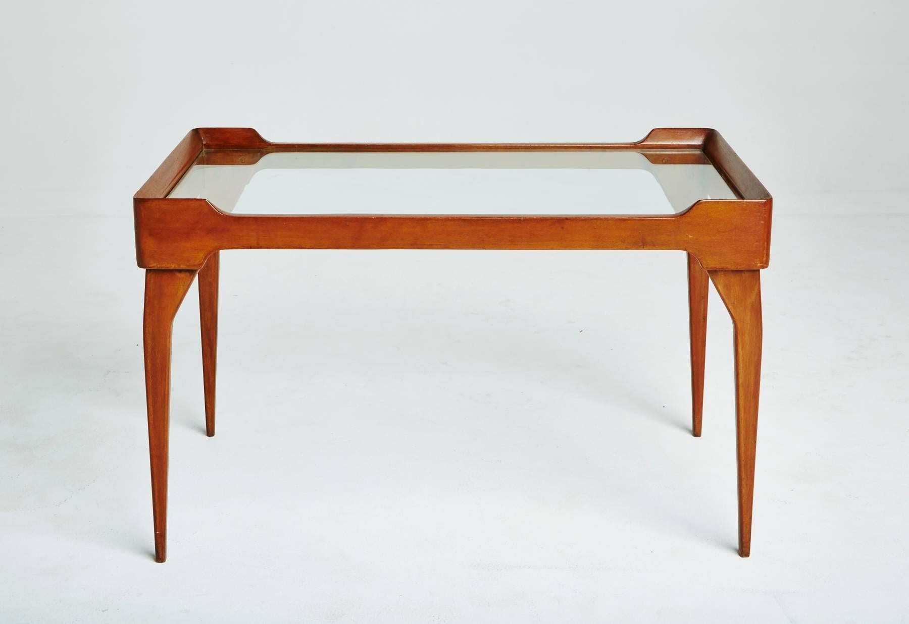 Created in the style of famed Italian designer Ico Parisi, circa 1950, this can be used as an end table, side table, coffee table, or a nightstand. The bright teakwood frame has angled tapered legs, and holds an inset glass table top with a ledge on