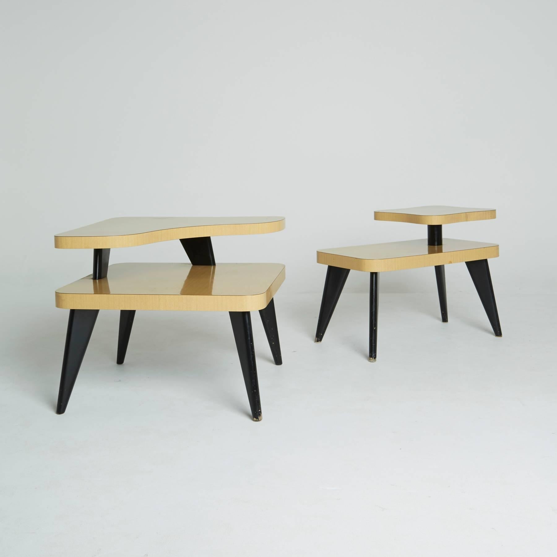 Each atomic, blonde laminate tables of these are two-tiered, with a biomorphic shape on the top surface. Their black tapered legs are an eye-catching contrast to the light wood appearance. Both of these are perfect as side tables, end tables, or