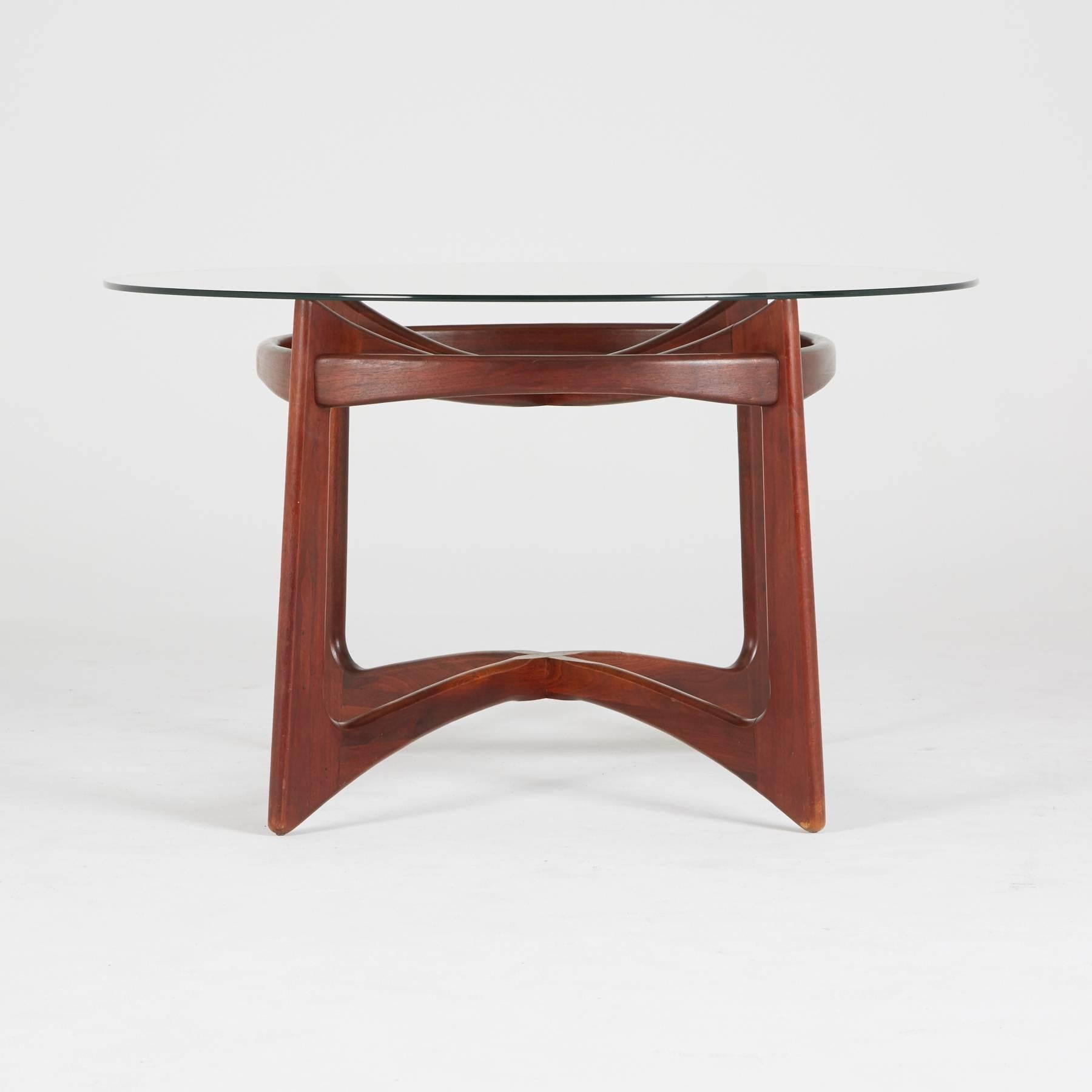 Designed by Adrian Pearsall for Craft Associates, circa 1960, a round glass surface rests on the sumptuous walnut base. This superb Compass dining table has the atomic, biomorphic qualities of Classic Mid-Century Modern design, though it coordinates