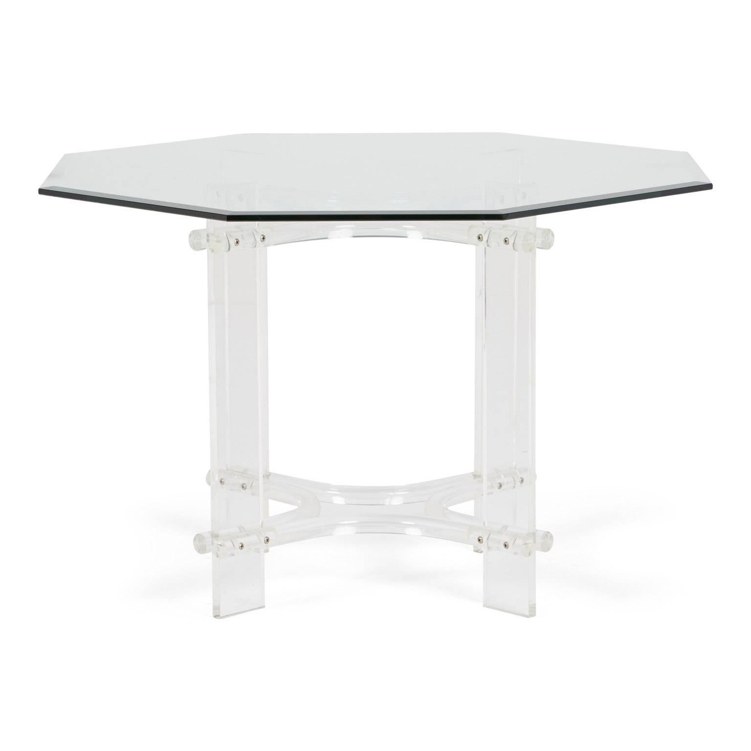 Gracefully constructed Lucite and glass dining table in the style of Charles Hollis Jones and Maison Jansen. This octagon shaped piece is comprised of a glass table surface atop a Lucite X base. The combination of Lucite and glass presents itself as
