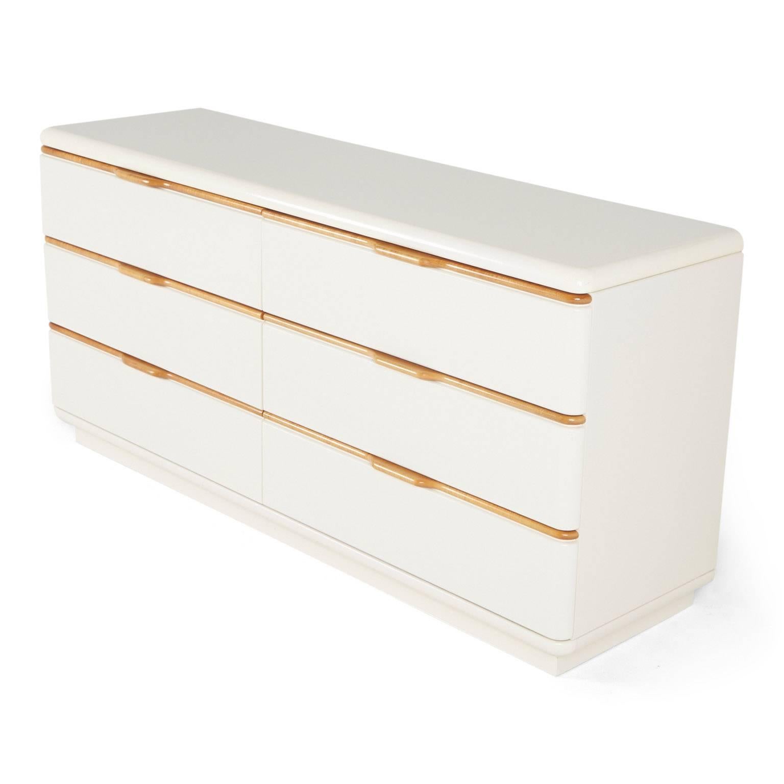 Produced by Lane, this six drawer low chest dresser or credenza is finished in cream colored lacquer with clear coat varnished wooden lip detail on the drawers. 

This piece can be integrated in to a bedroom living room, den, office or playroom