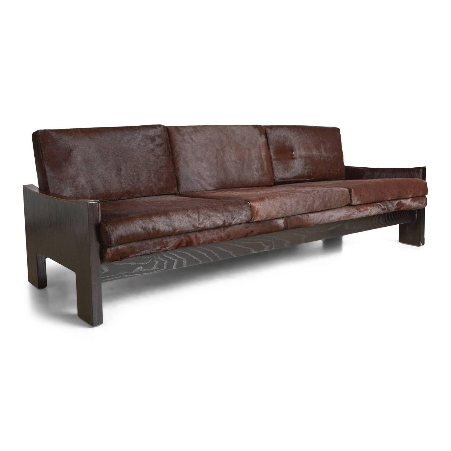 This highly detailed and exotic Brazilian sofa features glossy brown hair-on hide leather upholstery with subtle variations throughout, with ebonized oak frame and contrasting rosewood details on the armrests.

The simple, clean lines will fit