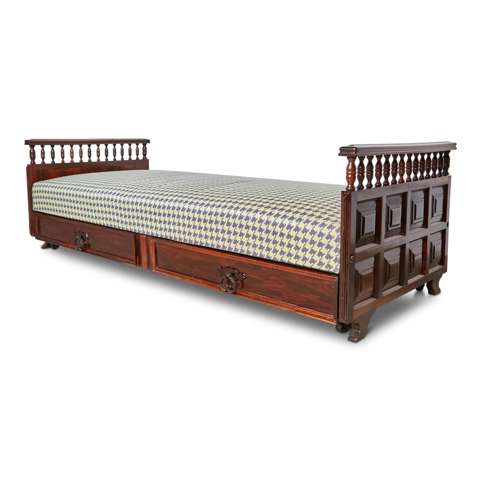 Fabricated from solid Rosewood, this newly restored substantial daybed features a pull-out storage compartment or add a mattress to create a trundle bed underneath the daybed frame for additional guests. 

Each end the frame has been carved with