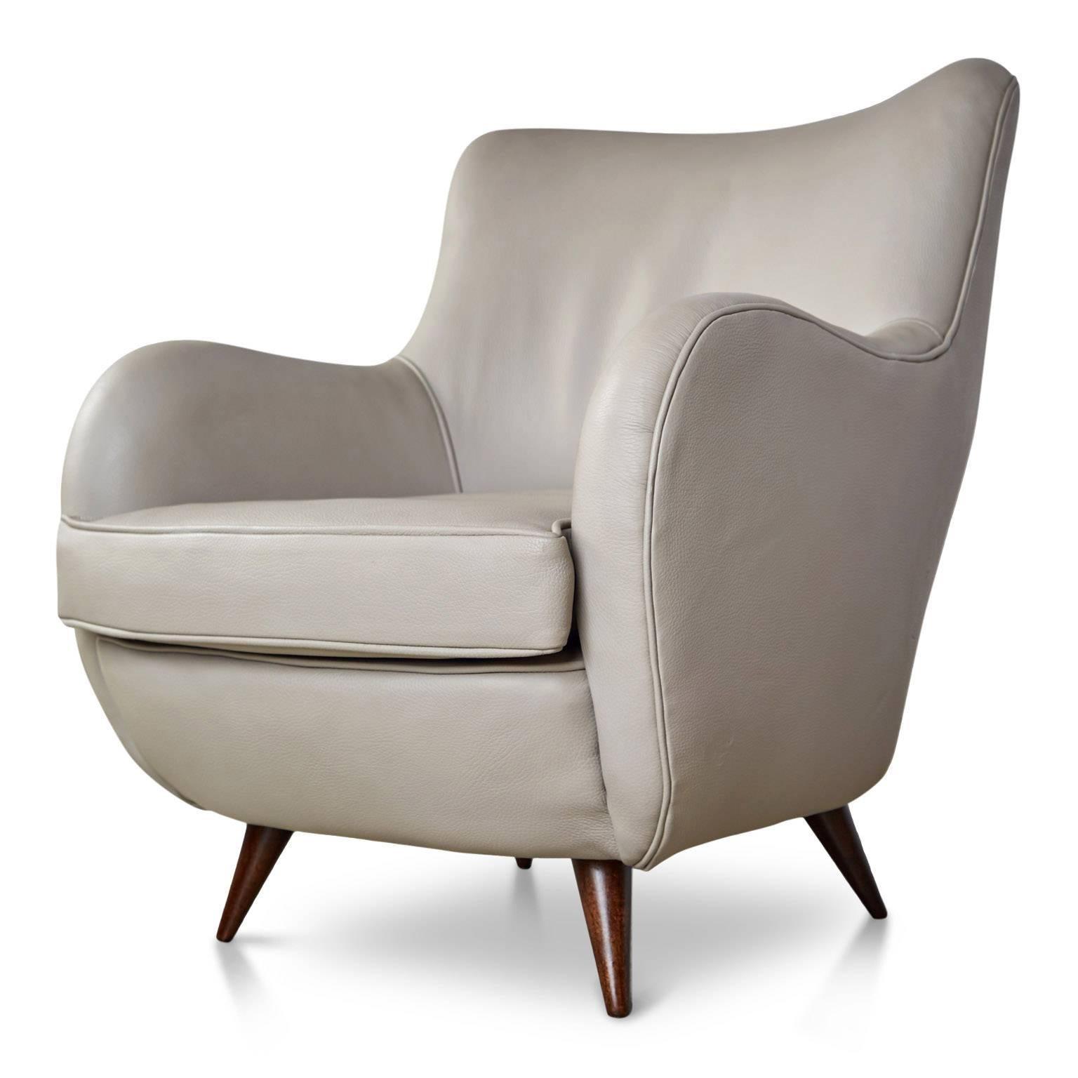 Two sculptural leather armchairs on solid Caviuna wood legs which have been recently refinished and the seat has been newly upholstered in an on-trend light gray leather. Featuring a curvaceous Silhouette and deep seating these lounge chairs are