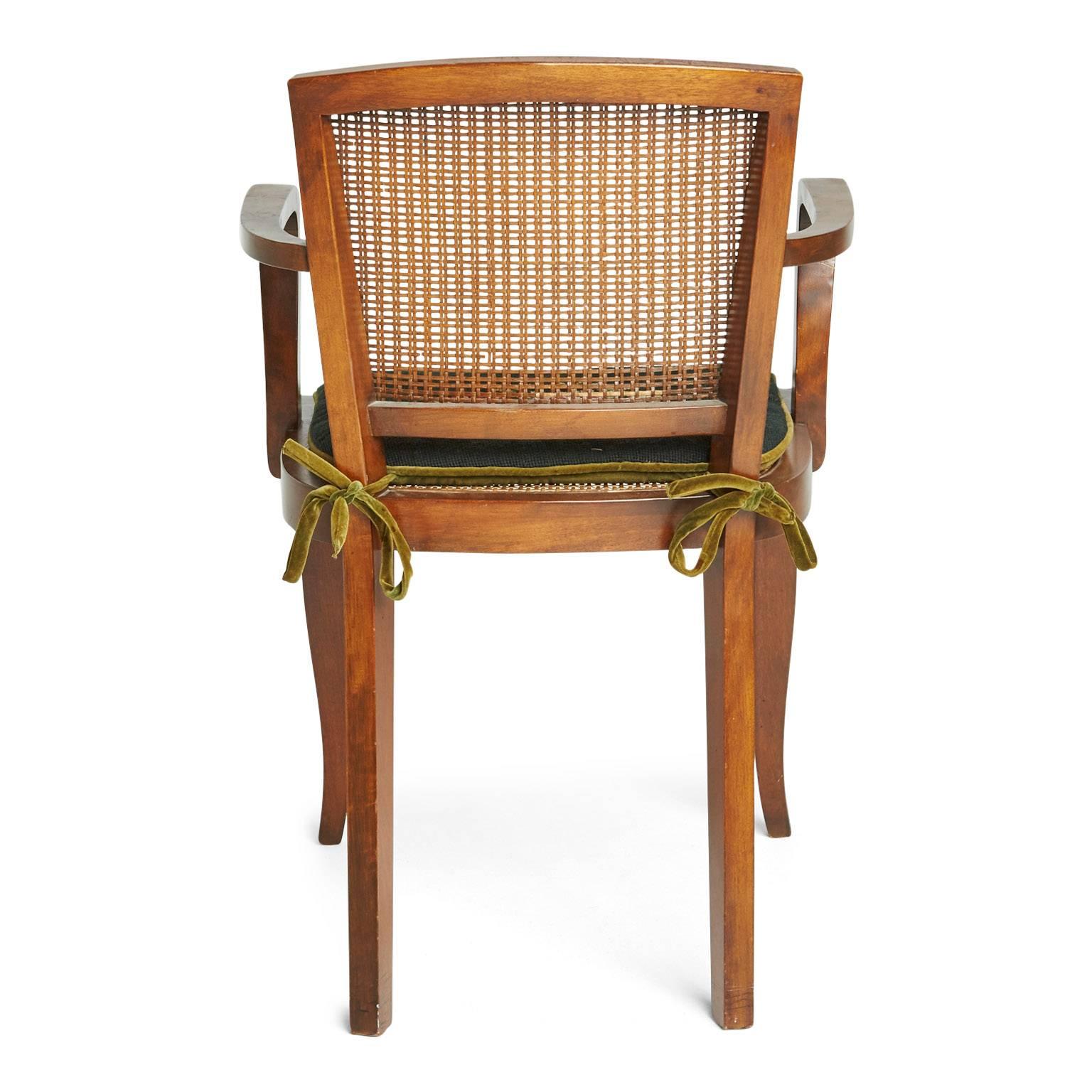Art Deco armchair of slender proportions with caned back and seat. This chair also features a handcrafted needlepoint cushion with floral detail as well as contrast dark chartreuse velvet welting, reverse side and tie backs. The hand woven caning is