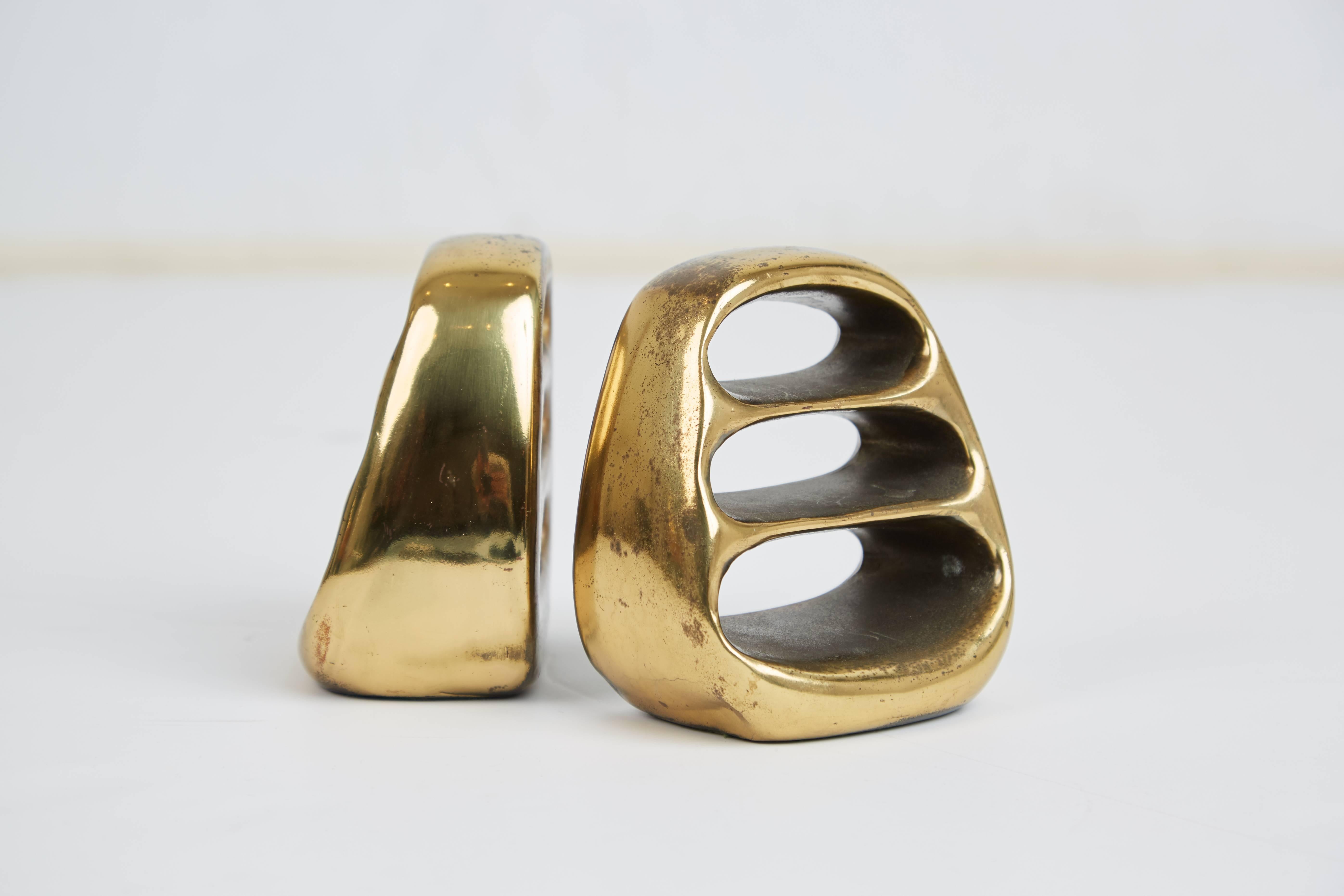 Lustrous pair of sculptural bookends in gleaming brass by Ben Seibel for Jenfred ware for Virginia Metalcrafters. This set features an admirable patina built up over time which can be highly desirable. These traces of age and use bring more vibrancy
