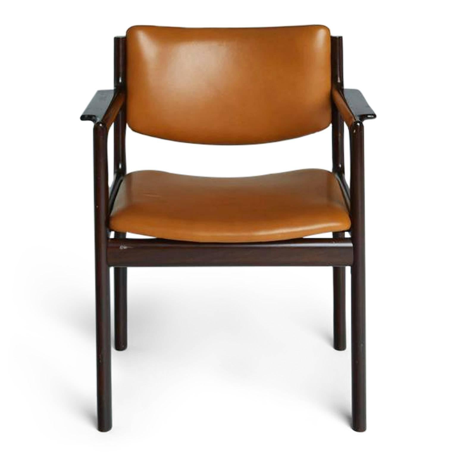 This set of caramel Mid-Century Modern armchairs are as durable in construction as they are attractive in their Danish modern design. The caramel leatherette upholstery of the seats and backs of each chair is framed by rich, dark rosewood with