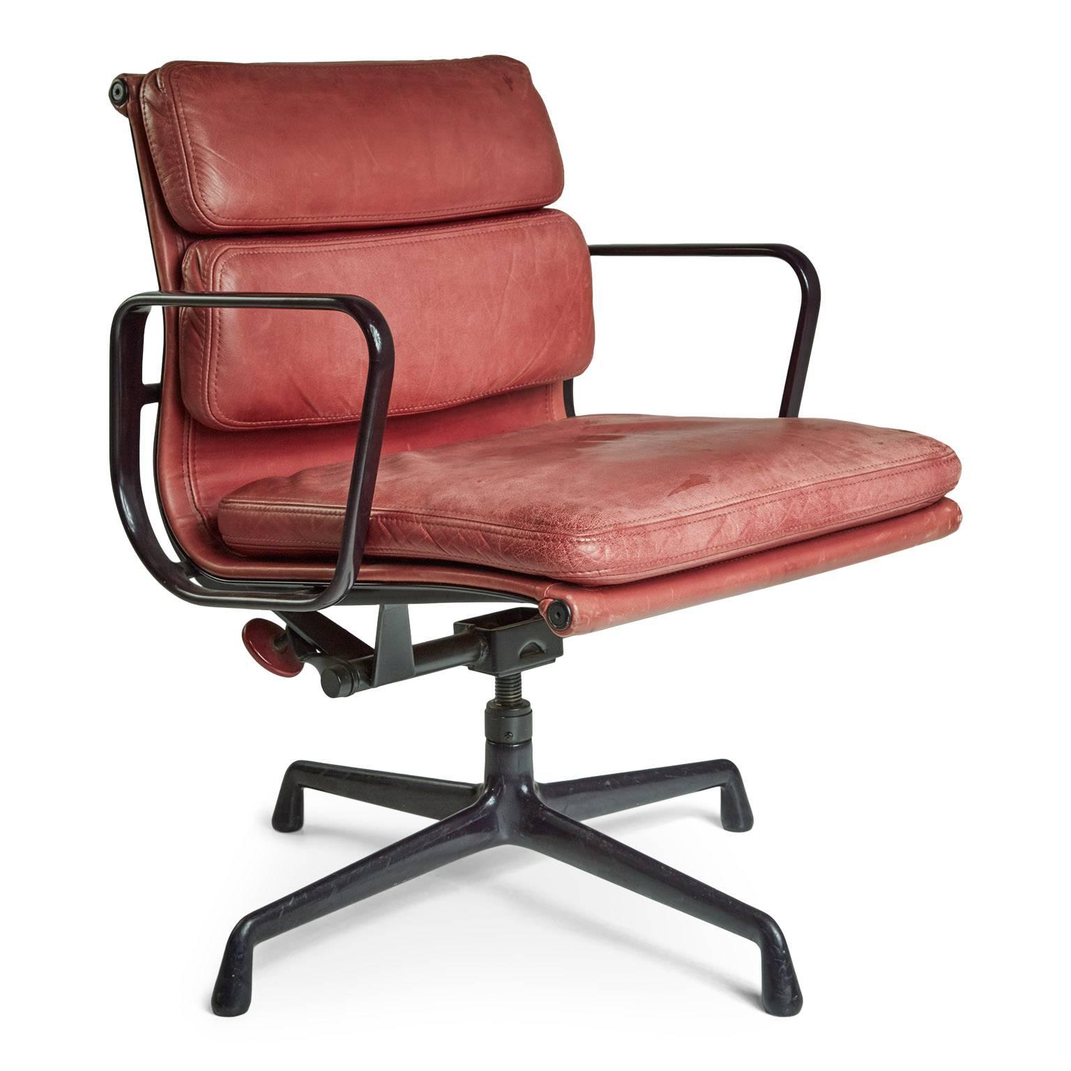 Pair of His and Hers matching soft pad aluminium group management and executive desk chairs designed by Charles and Ray Eames for Herman Miller. Featuring the original burgundy leather upholstery that has developed an admirable patina. These traces