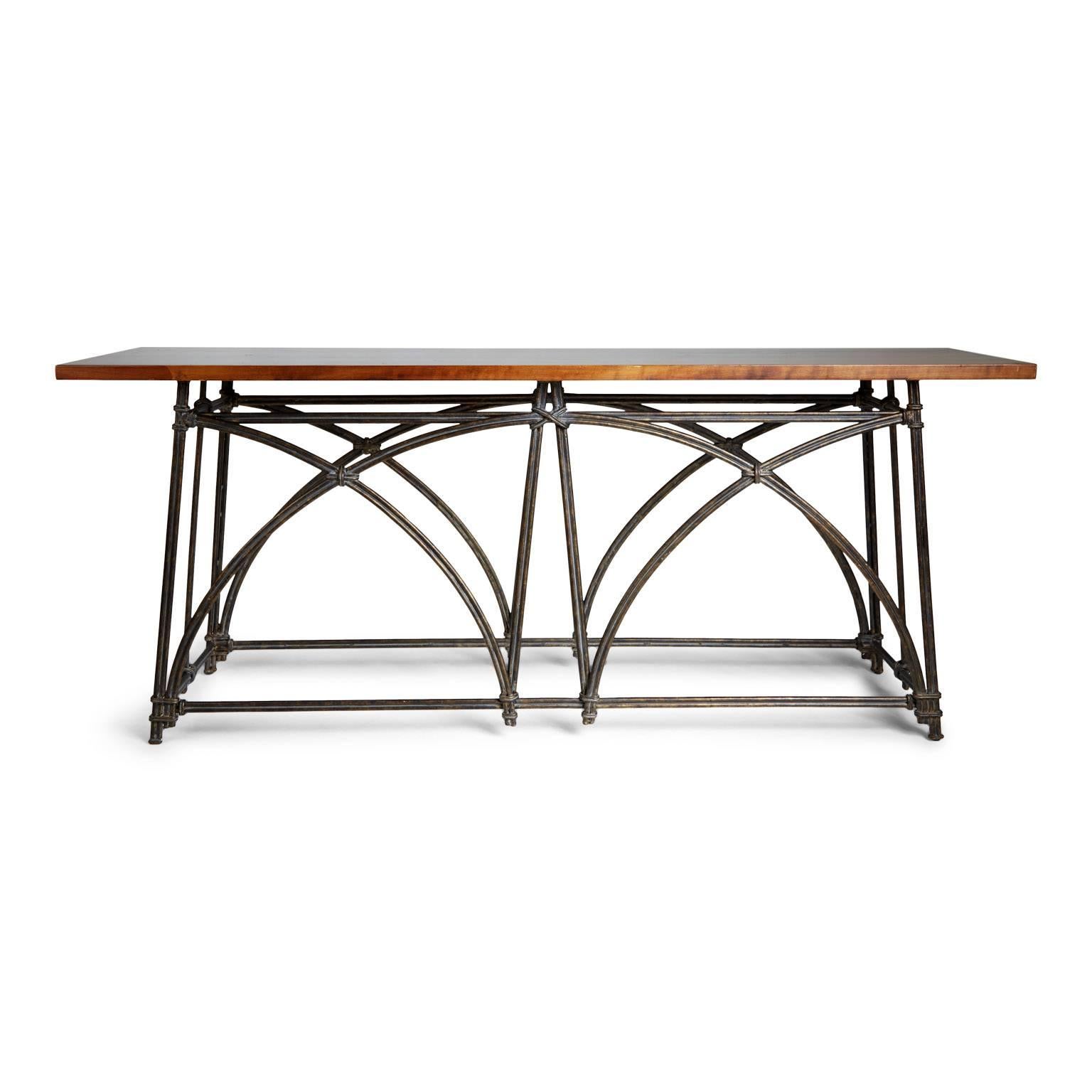 Extensive colonial styled console table featuring a scrolled iron base and solid wooden top. The base features decorative lengths of curvaceous iron which overlap and are finished with an embellishment which gives the appearance of being tied