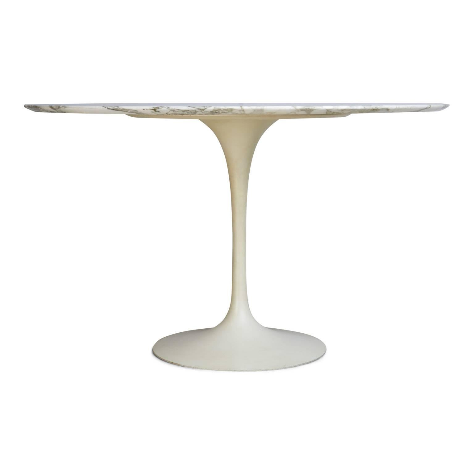 One of the most highly coveted vintage items at present, this elegant dining table designed by Eero Saarinen in 1954 for Knoll features a broad circular top of Carrara marble supported by a cast aluminum tulip base finished in white Rilsan. This