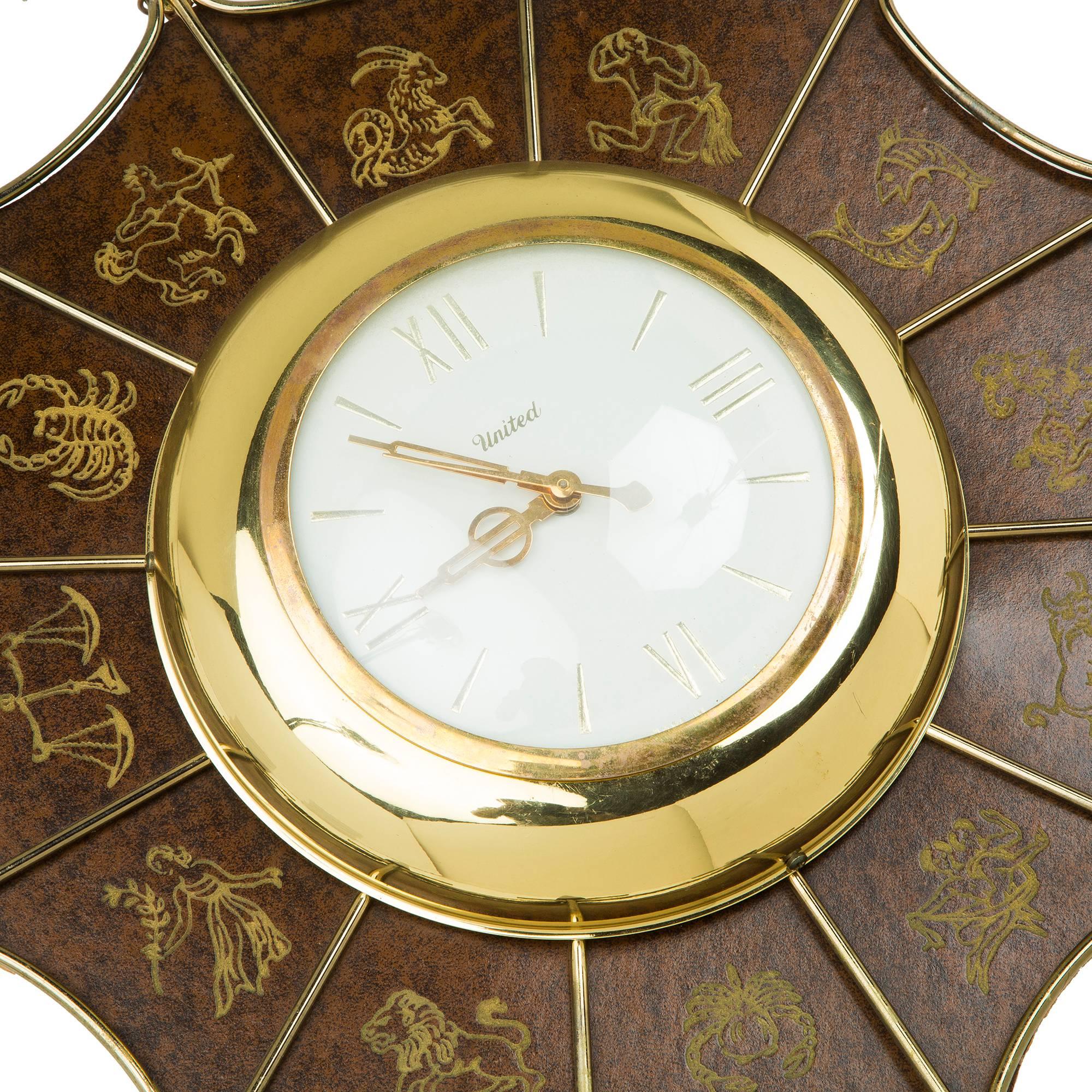Wonderful starburst clock by United. Featuring twelve wood spindles, faux leather surface finish with embossed symbols of the zodiac, wire frame with white and brass face and Roman numerals. Would pair wonderfully in a chinoiserie styled room, a