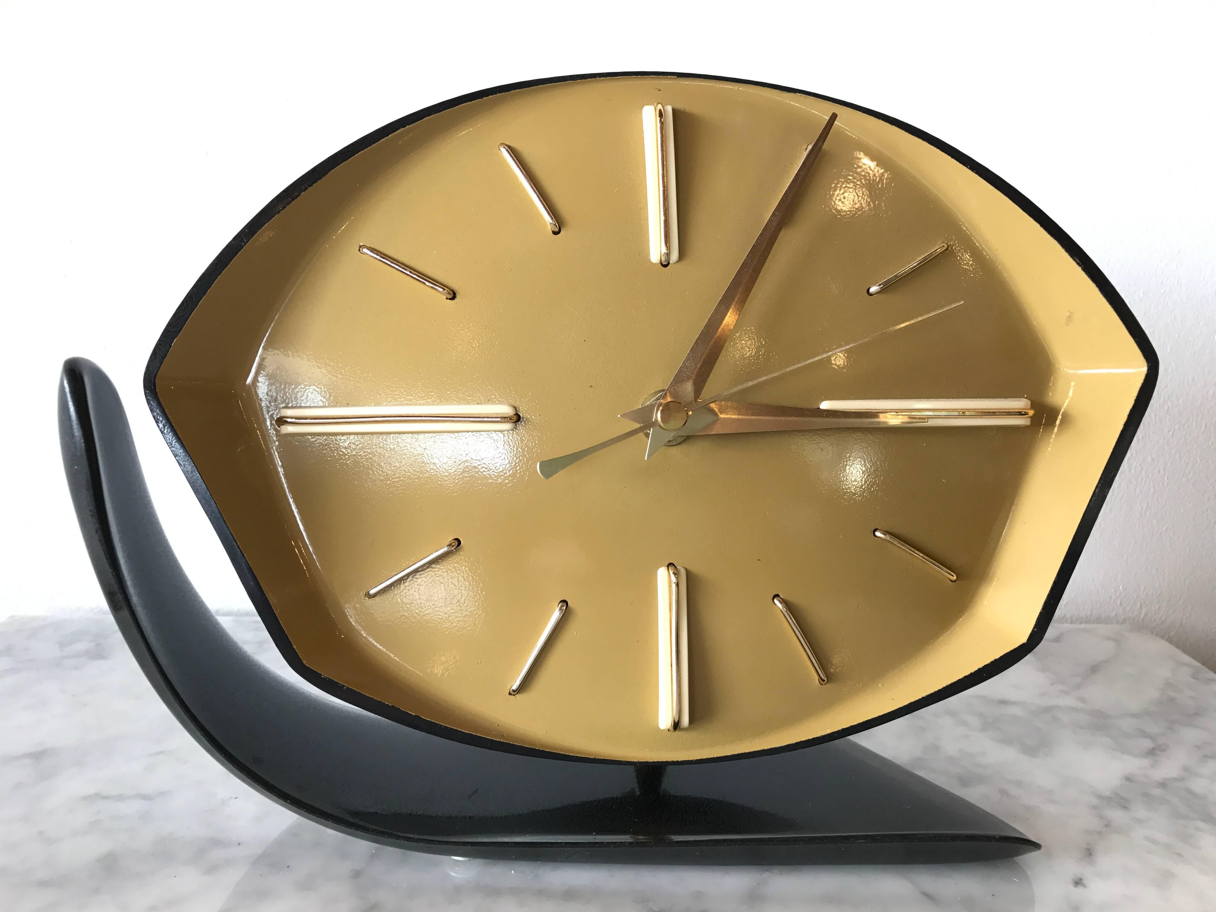 Elegantly crafted geometric Art Deco bakelite desk clock, circa 1940. Featuring a wide ochre colored angular face punctuated by cream bakelite and brass markers with brass minute and hour hands. This clock is positioned on a brass stem with a ball