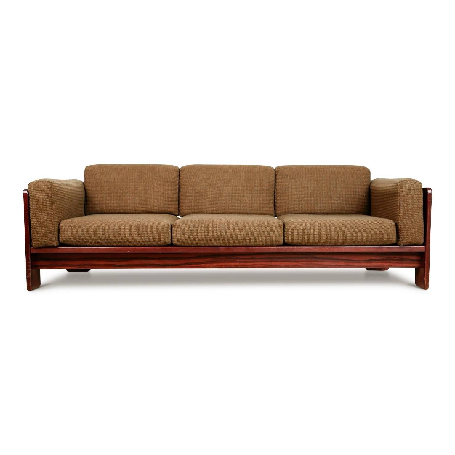 Recently reupholstered and refinished Bastiano sofa by Tobia Scarpa for Gavina. This elegantly crafted sofa has been fabricated from rosewood which displays a beautiful grain, showing a variety of shades and movement in the wood. The back of this