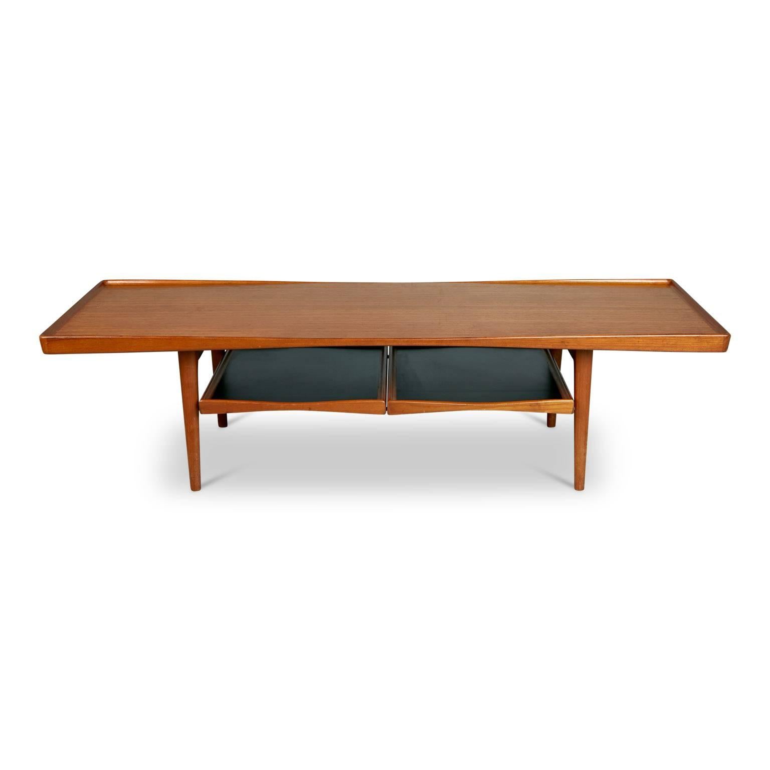 Innovative and sleek designed coffee table by Poul Jensen for Selig. This elegantly executed cocktail table is fabricated from teak and has two layers including a solid top and then an additional level underneath which holds two identical black