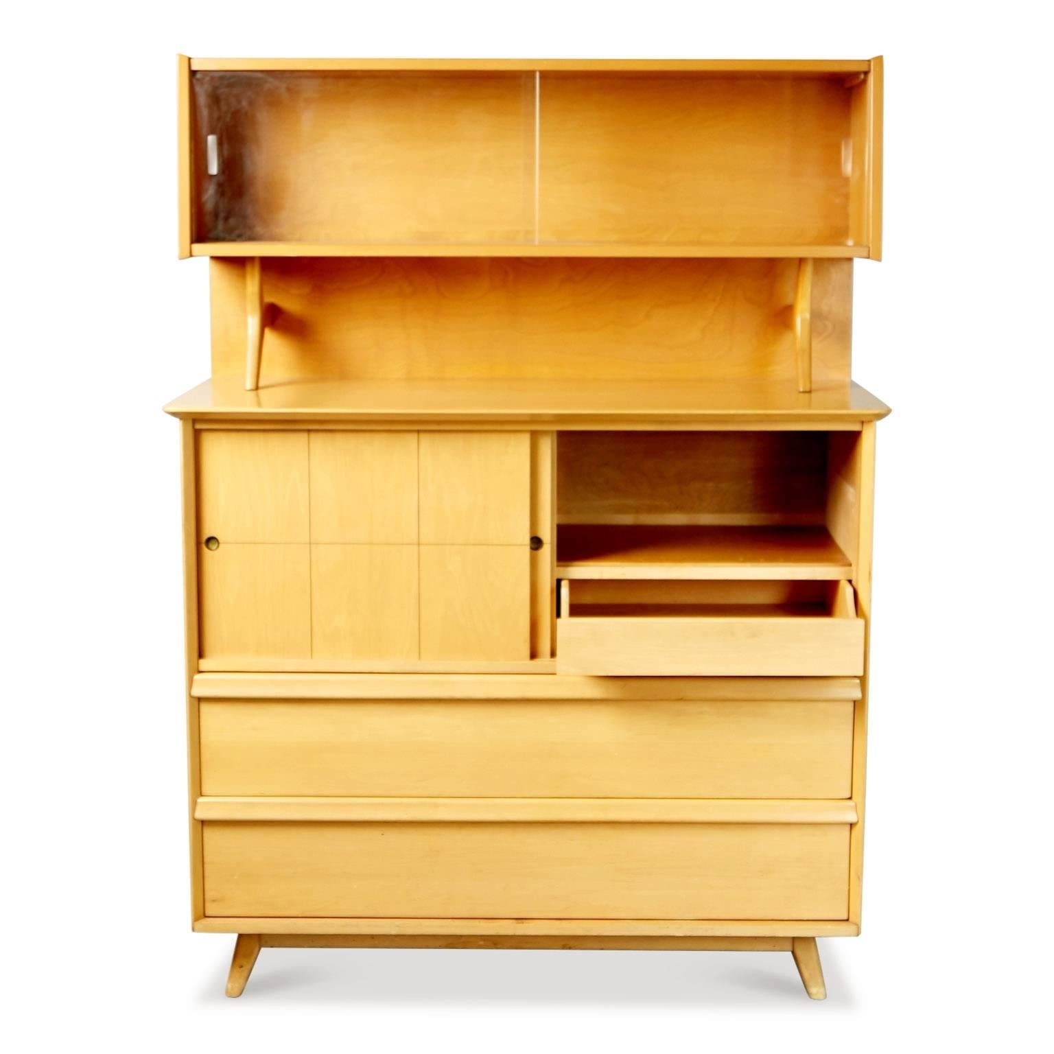 A very cute sculptural Mid-Century Modern cabinet with display hutch by Baumritter, circa 1955. 

This display cabinet is fabricated from golden toned maple with multiple compartments and shelving options, offering a wealth of storage options. The