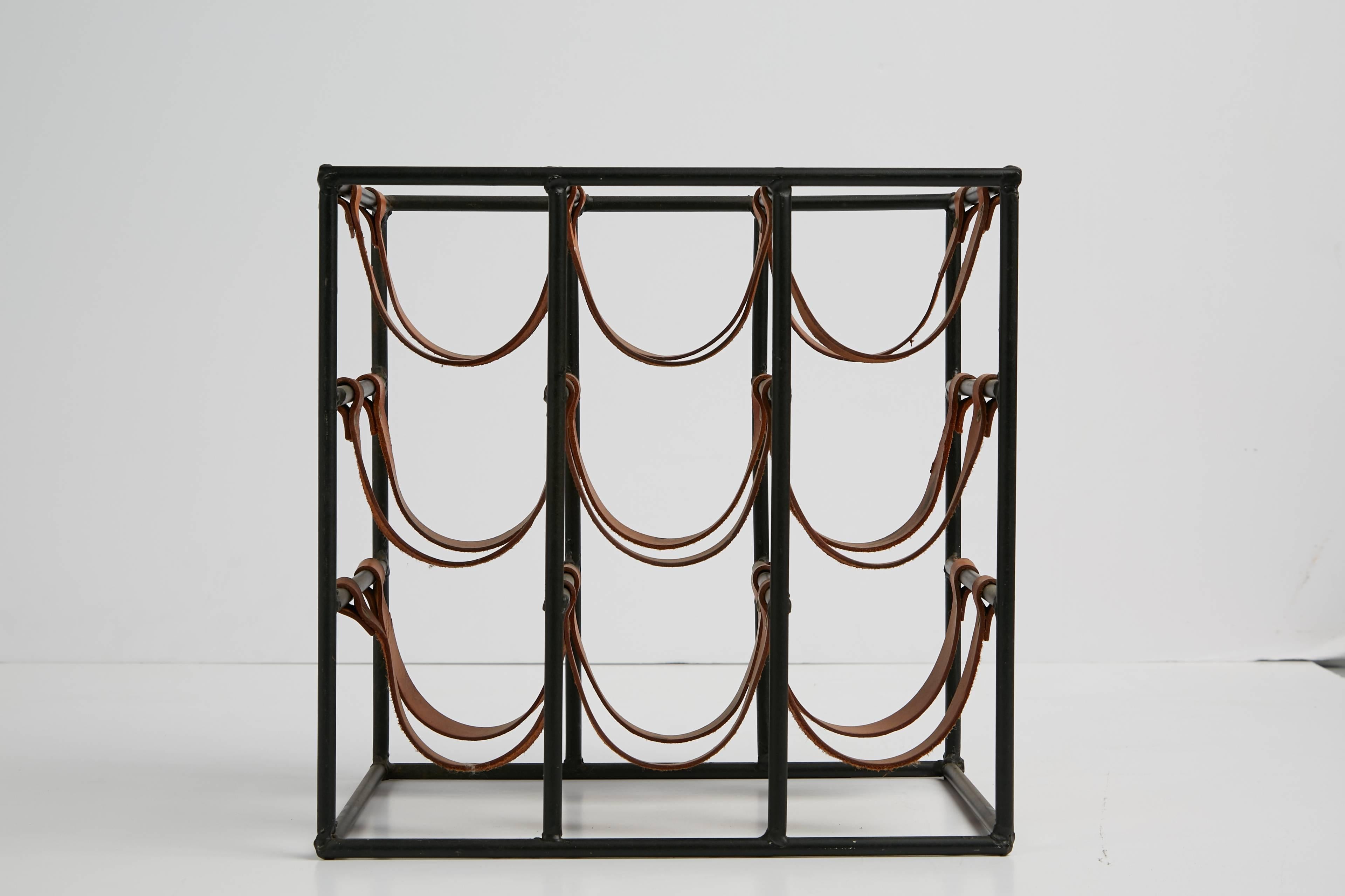 Sculptural iron and leather wine rack by Arthur Umanoff for Shaver Howard. Featuring a solid iron frame with original saddle leather straps to hold nine bottles. The unique design can be viewed at any angle and would make a great display piece for a