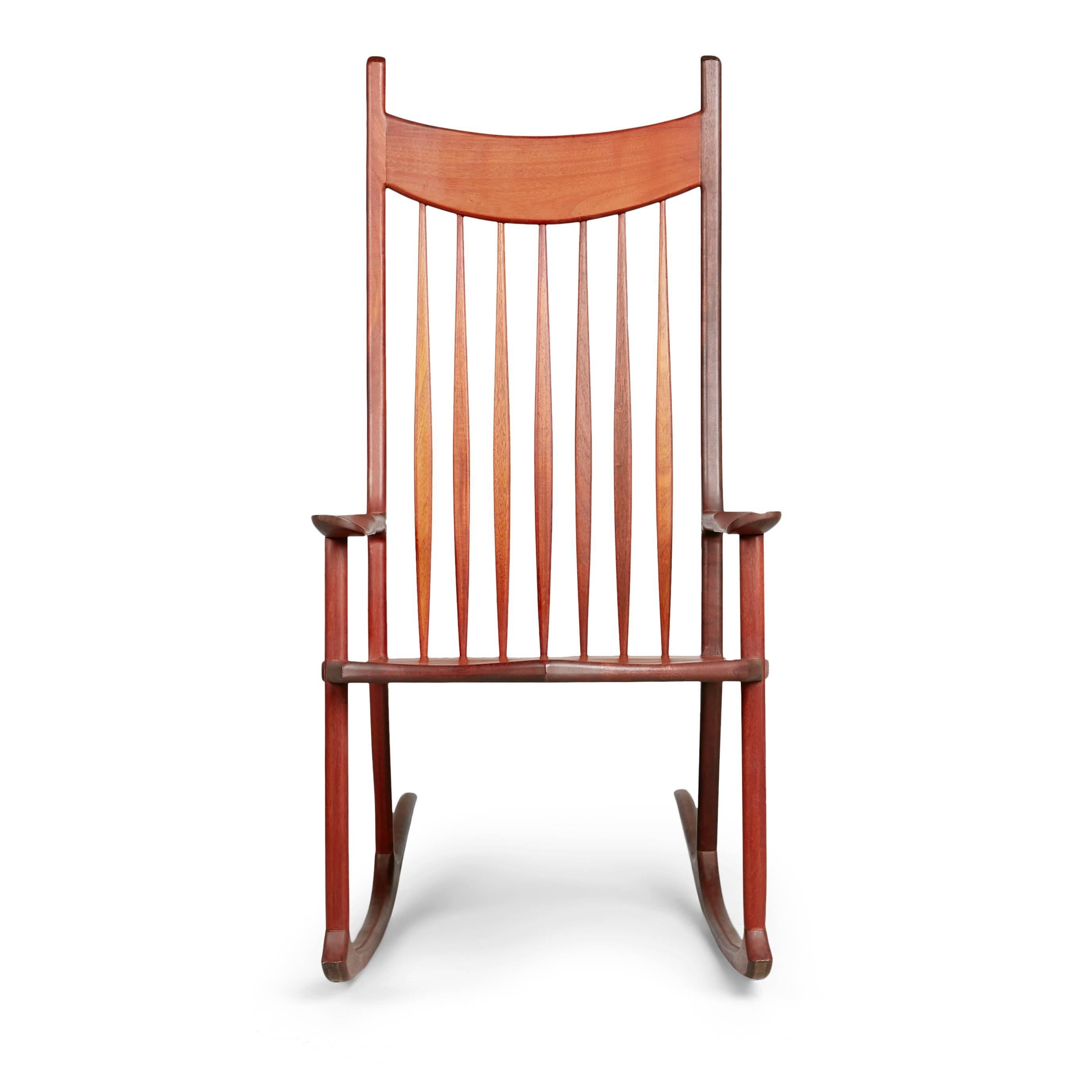 Oversized Sam Maloof styled American craftsman rocking chair. This generously proportioned armchair consists of a tall spindled back with a broad seat and armrests which have brass dowel accents. The runners of this rocker curve gracefully and