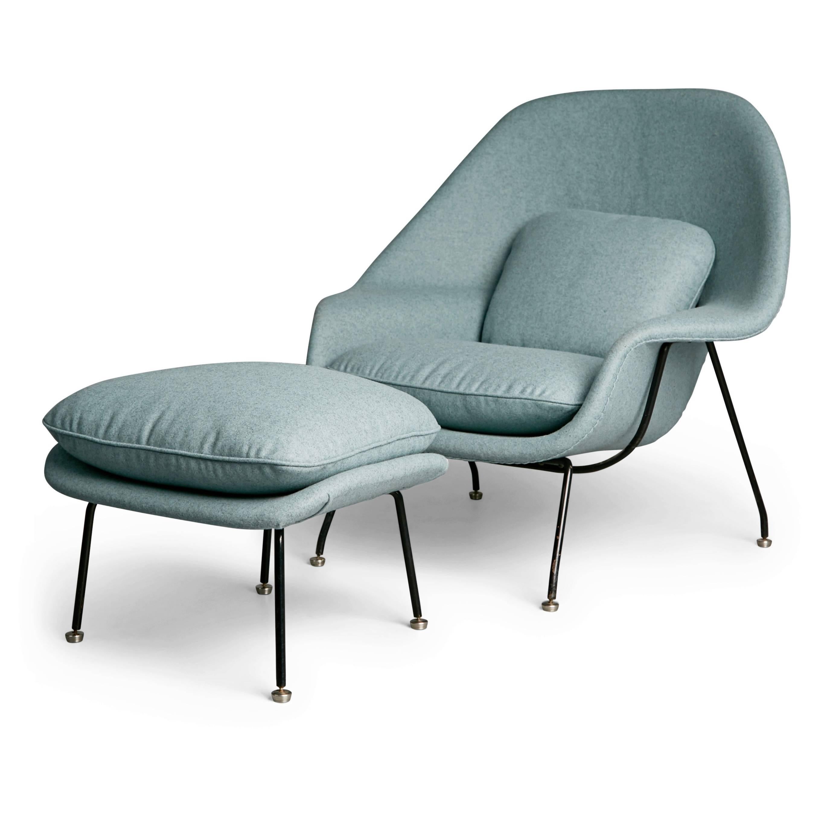 Newly upholstered early production womb chair by Eero Saarinen for Knoll Associates. This example possesses an early production black frame which looks striking against the blueish wool. The flat glides (feet) help to attribute this set to being a